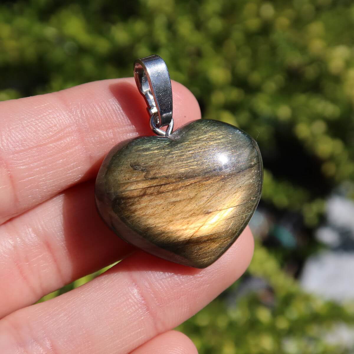 Hand holding Labradorit heart pendant with unique golden sheen, showcasing intuitive and spiritual properties.