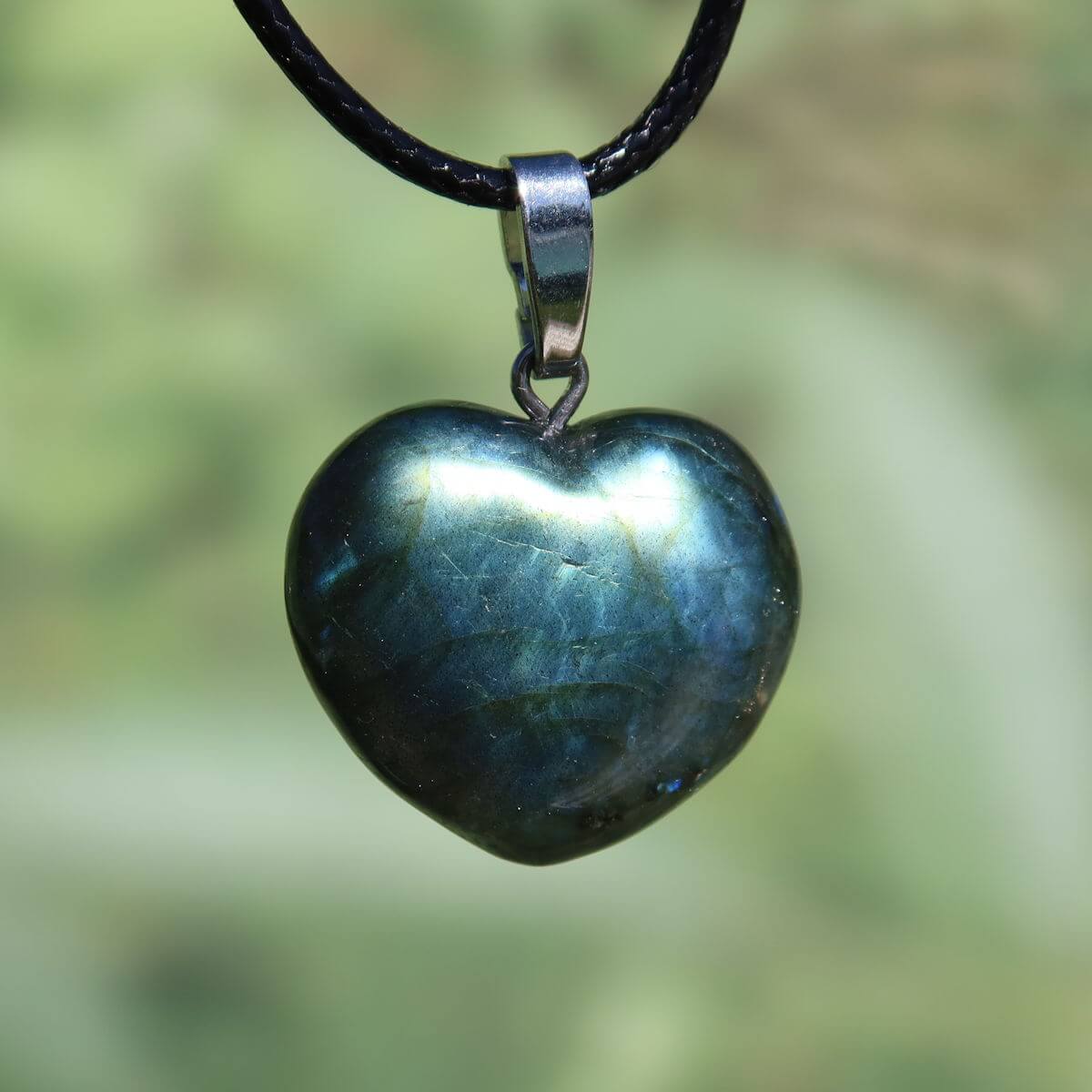 Heart-shaped Labradorite pendant showing blue-green hues reflecting light, symbolizing intuition and spirituality.