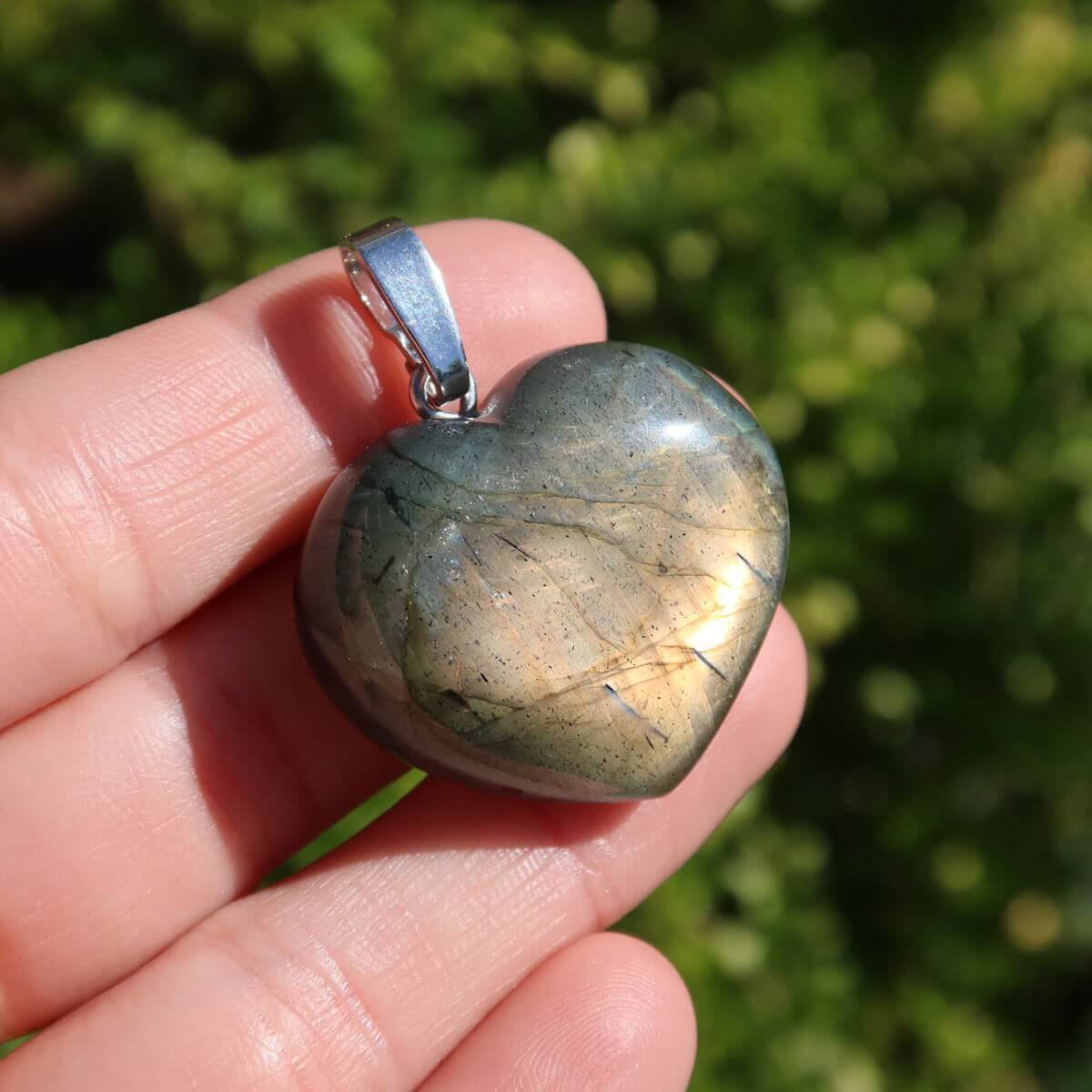 Labradorite heart pendant showing vibrant blue and gold hues in sunlight, highlighting unique patterns and colors.