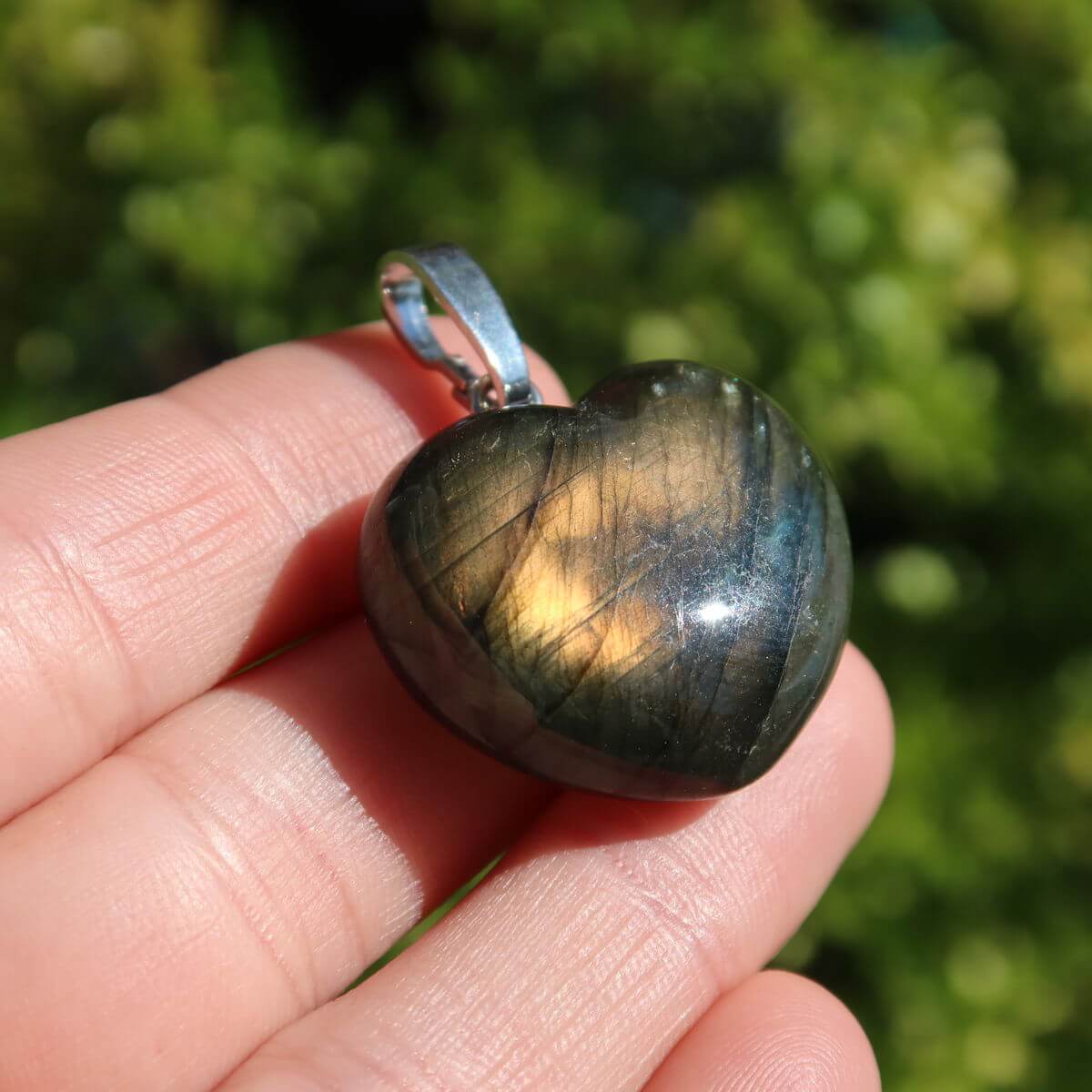 Labradorite heart pendant in hand, 22mm unique gemstone jewelry with changing colors, symbolizing intuition and spirituality.