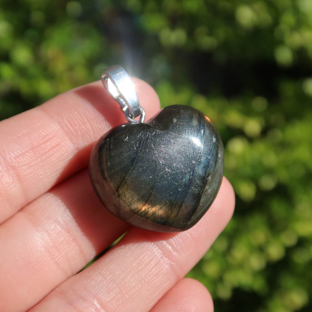 Labradorite heart pendant in hand, 22mm unique gemstone jewelry with changing colors, symbolizing intuition and spirituality.
