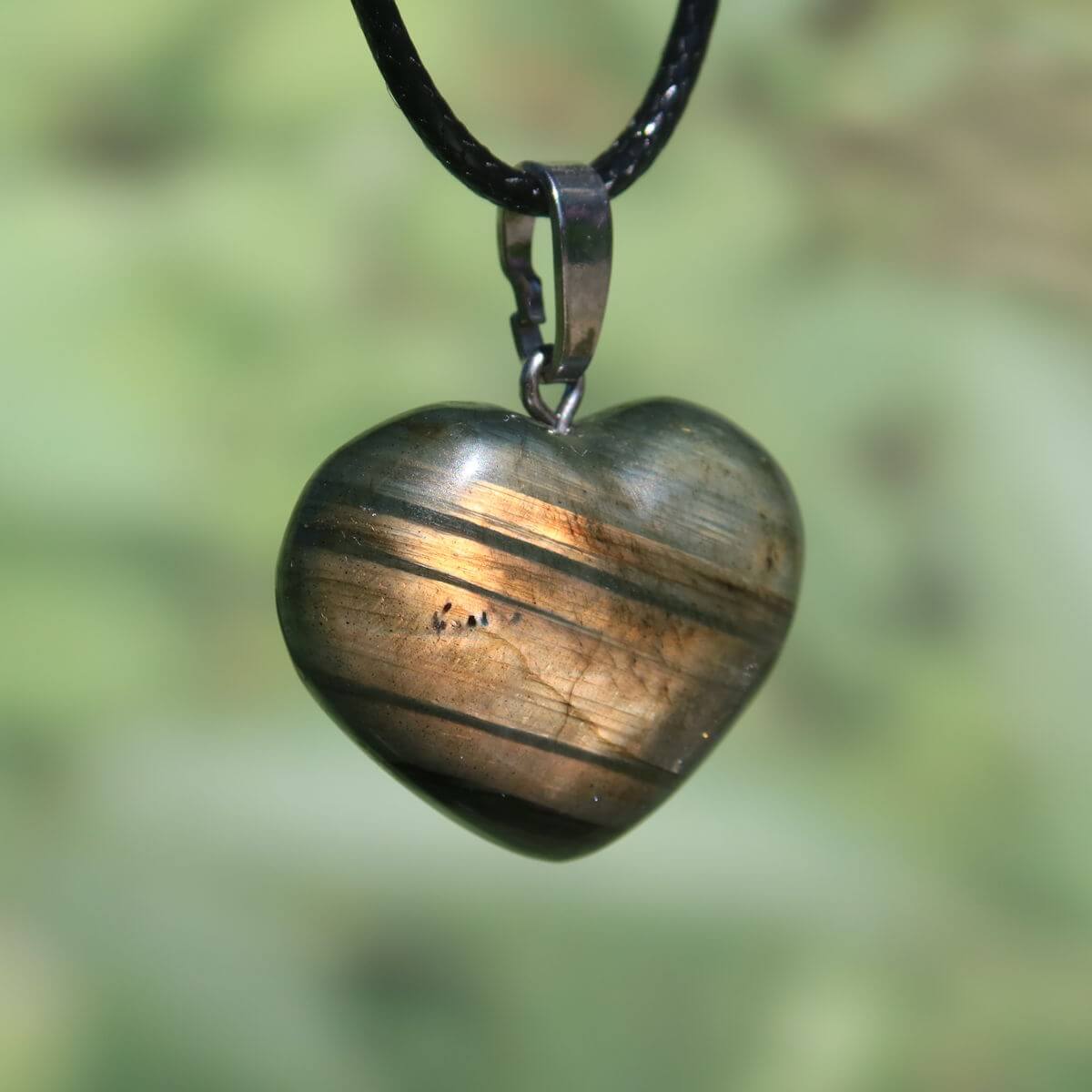 Heart-shaped labradorite pendant showcasing iridescent colors on a black cord, symbolizing intuition and uniqueness.