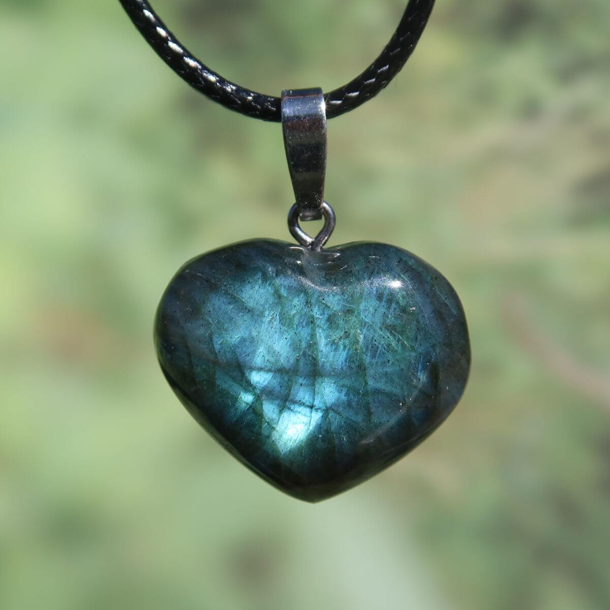 Heart-shaped Labradorite pendant with vibrant blue and green hues on a black cord necklace, promoting intuition and spirituality.