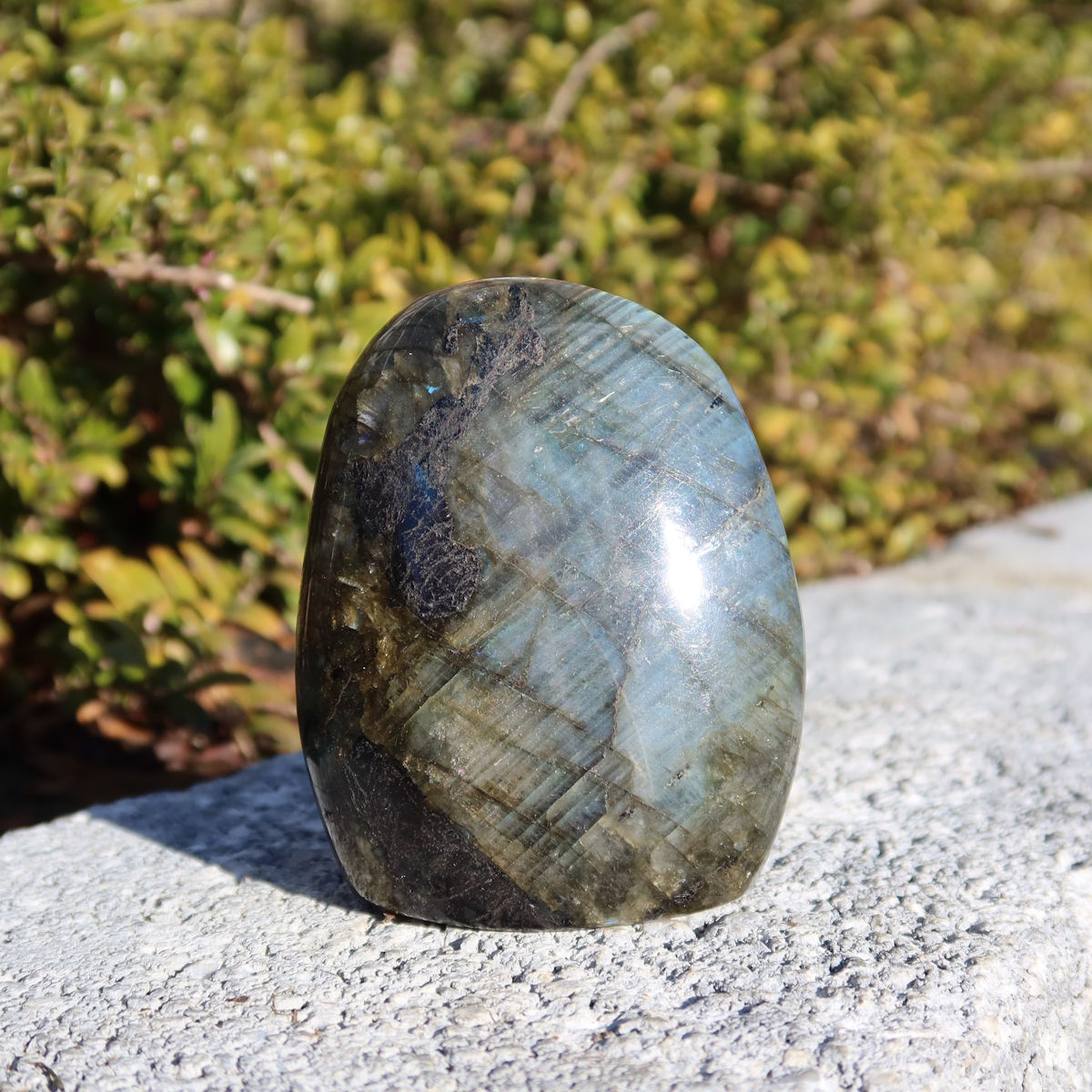 Labradorit Freiform poliert - 7x5cm - Intuition und Kreativität Nr.5 vor grünem Hintergrund.