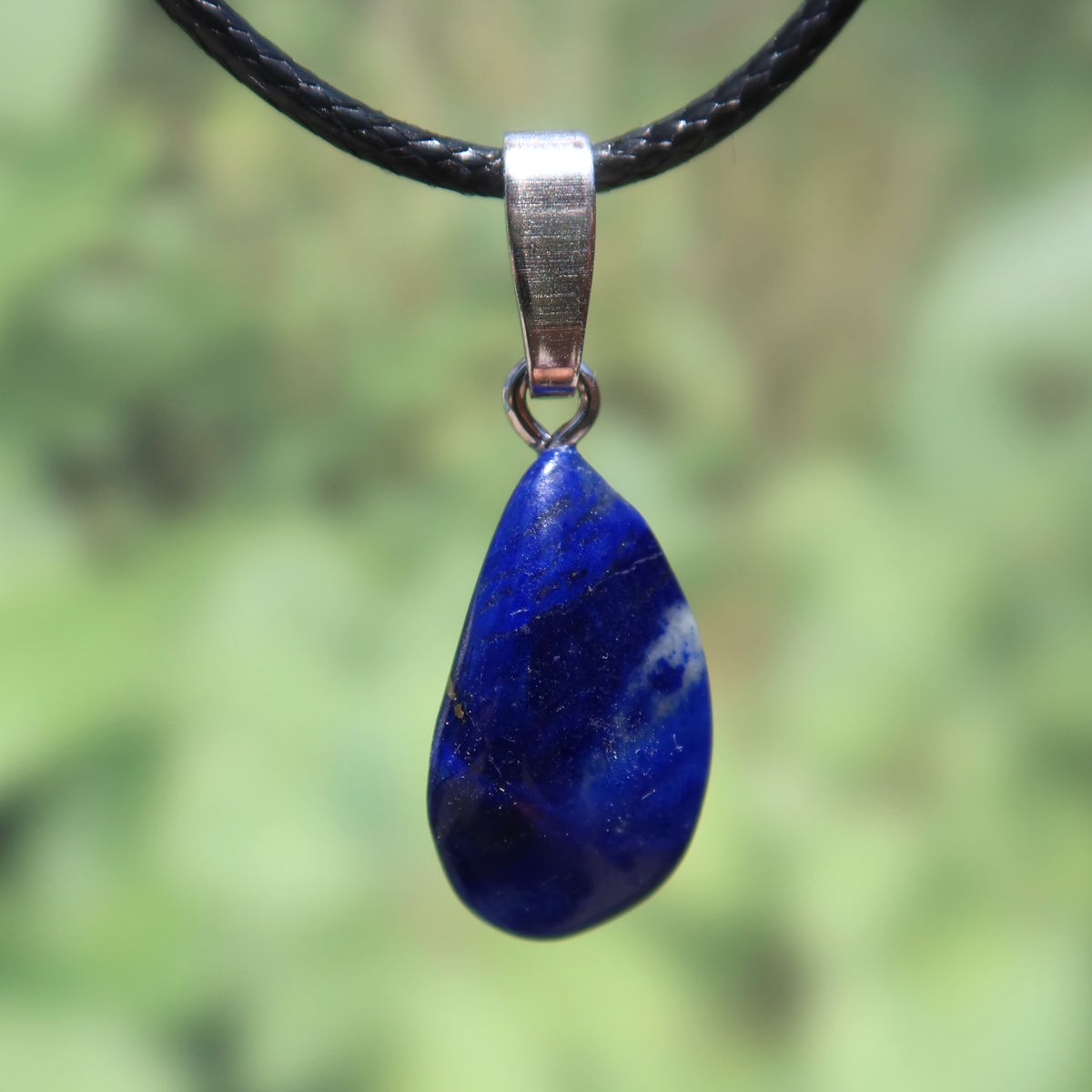Natürlicher Lapislazuli Anhänger mit goldenem Schimmer, handgefertigt mit Silberöse, 21mm, Unikat, auf grünem Hintergrund.