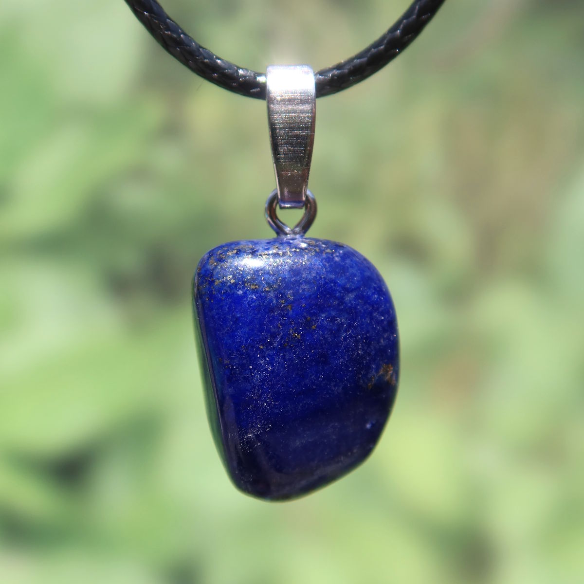 Natürlicher Lapislazuli Anhänger 20mm mit goldenen Sprenkeln und Silberöse, Unikat Nr. 30, vor unscharfem grünem Hintergrund