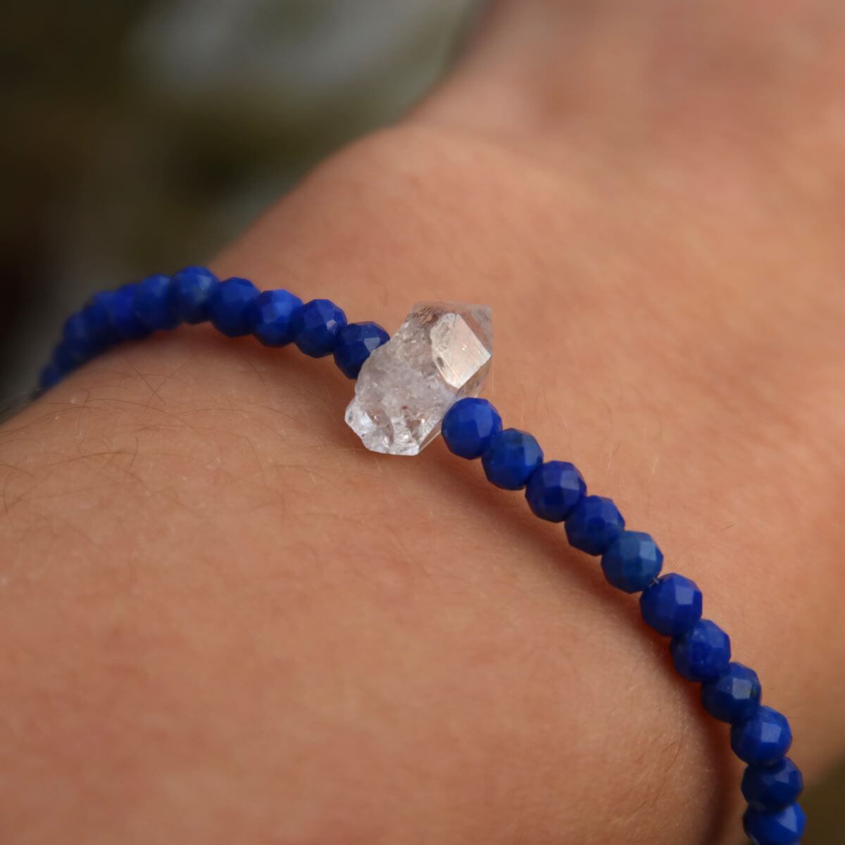 Handmade lapis lazuli and Herkimer diamond bracelet on wrist, featuring deep blue faceted beads and a central Herkimer quartz crystal, 17cm.