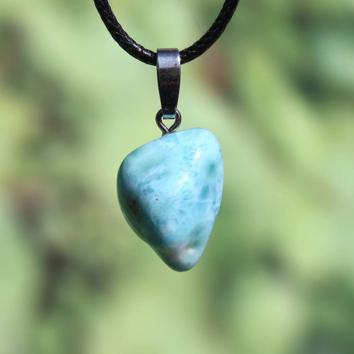 Larimar pendant with silver bail, 21mm in size, showcasing unique light blue color, set against a natural blurred background.