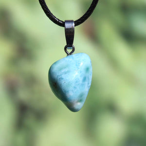 Larimar pendant with silver bail, 21mm in size, showcasing unique light blue color, set against a natural blurred background.