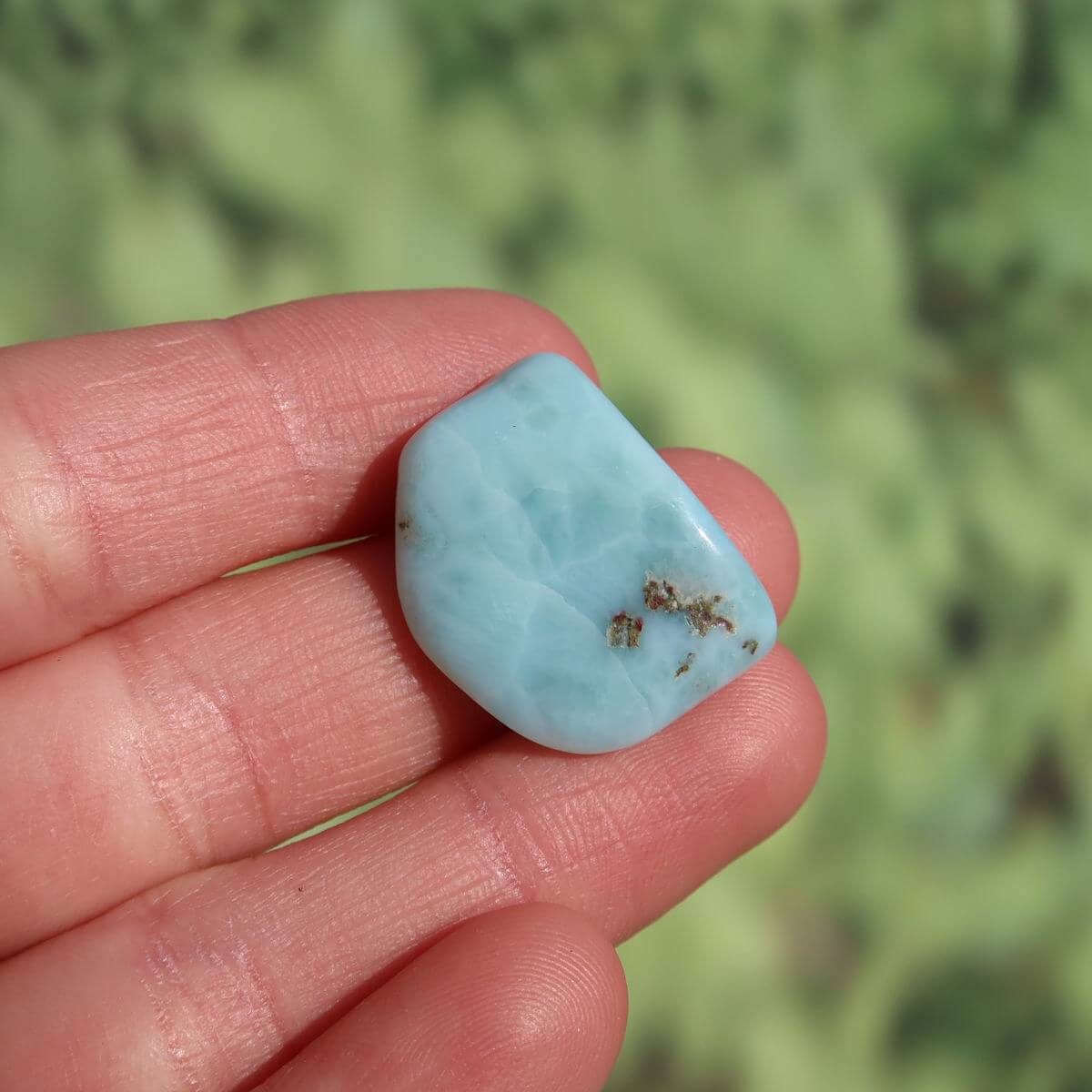 Hand holding a genuine 22mm Larimar gemstone, known for enhanced perception and protection, unique piece from Dominican Republic.