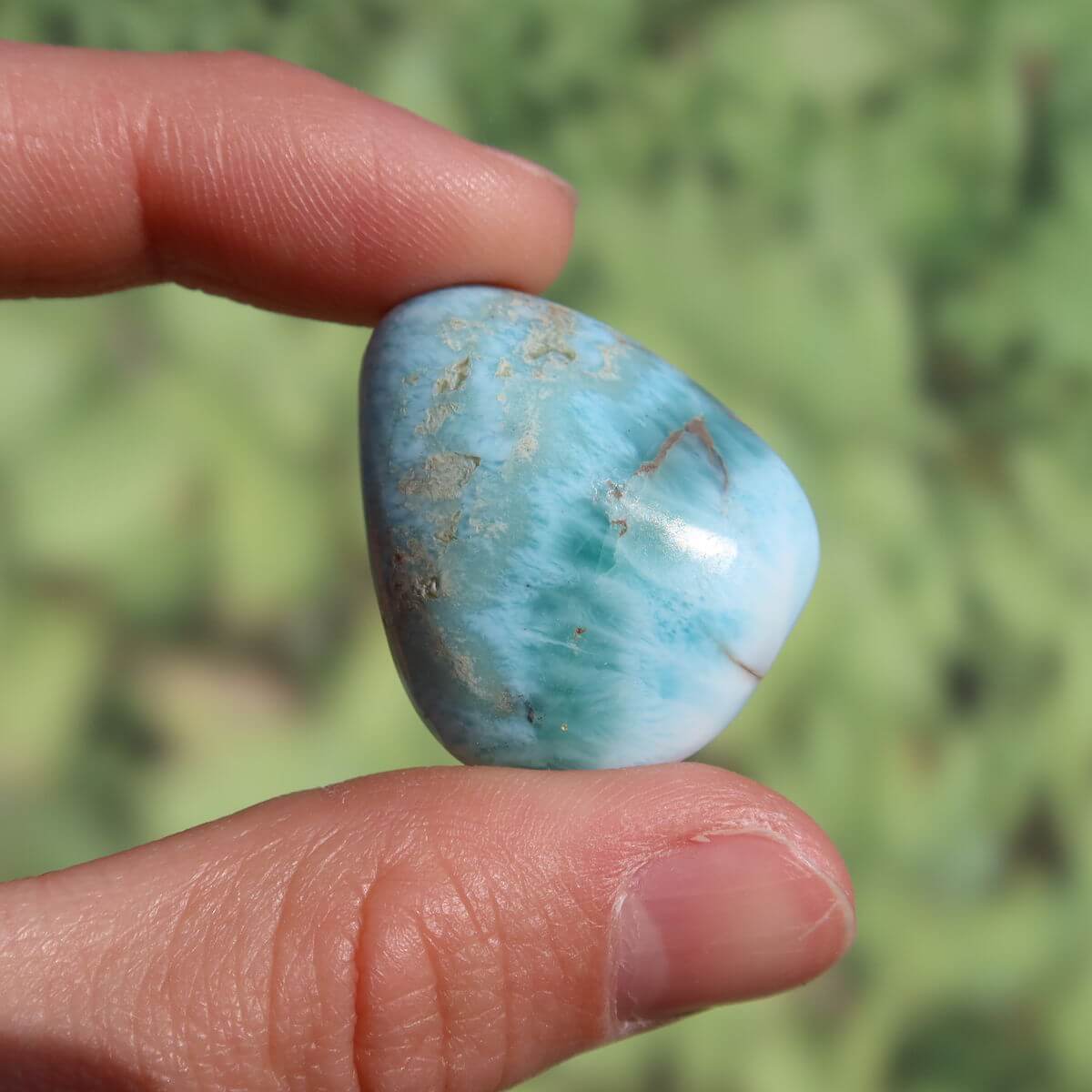 Hand holding a unique 30mm Larimar gemstone from the Dominican Republic, showcasing blue hues and natural beauty.