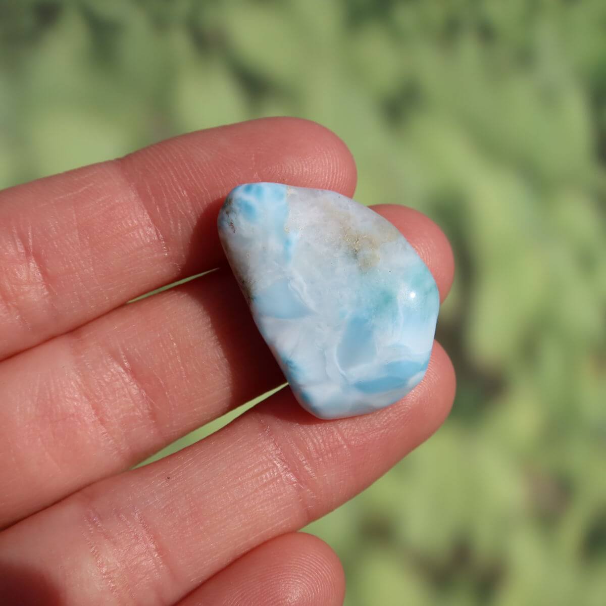 Hand holding a 26mm Larimar stone showcasing its unique blue and white patterns.