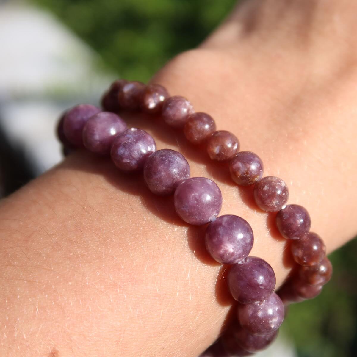 Person wearing two Lepidolith gemstone bracelets in shades of purple, showcasing varying bead sizes of 4-6-8mm for spiritual balance.
