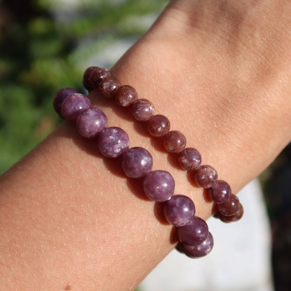 Person wearing two Lepidolith gemstone bracelets in shades of purple, showcasing varying bead sizes of 4-6-8mm for spiritual balance.