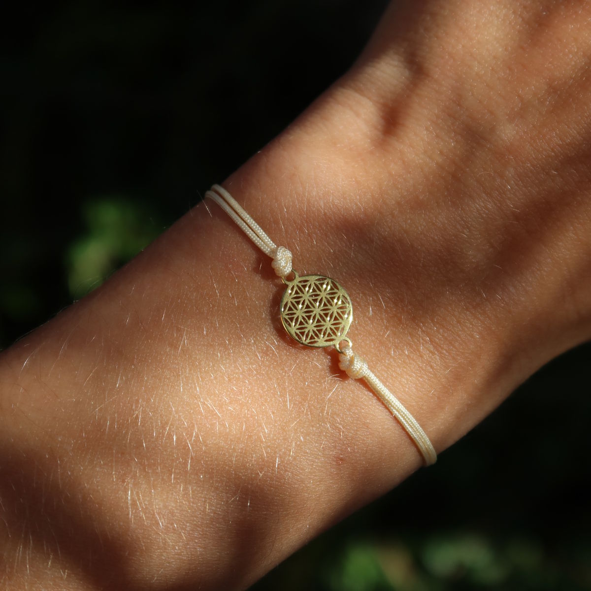 Makramee Armband mit Blume des Lebens vergoldet - Handgemacht und Größenverstellbar - Nr. 2, getragen am Handgelenk im Sonnenlicht.