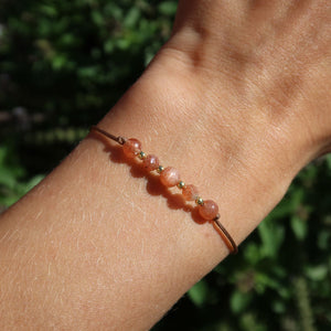 Handgemachtes Makramee Armband mit Sonnenstein - Lebensfreude und Selbstvertrauen - Nr. 6, funkelt im Sonnenlicht auf einem Handgelenk.