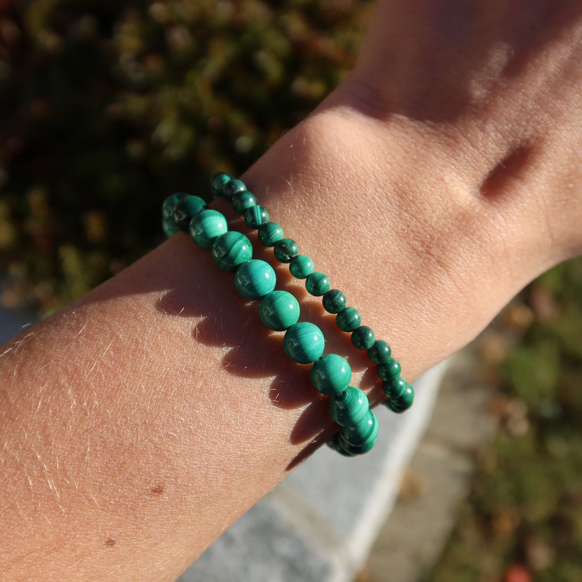 Malachit Edelstein Armband - 1 Stück - in Varianten 4-6-8 oder 10mm, grüner Malachit auf Hand im Sonnenlicht.