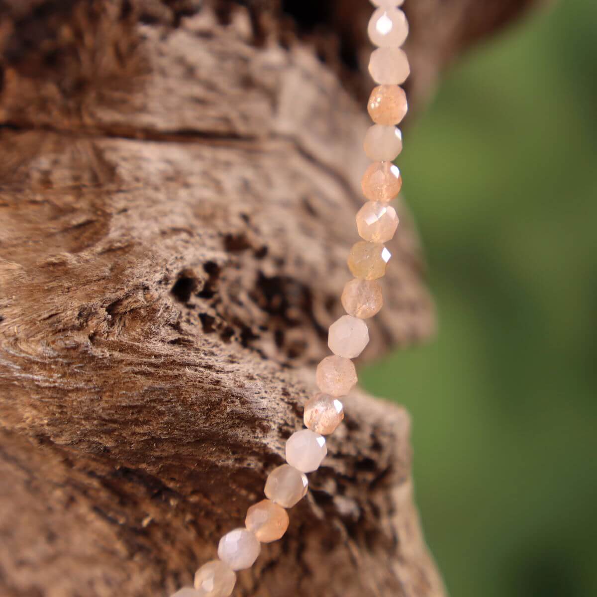 Peach-colored moonstone necklace with elegant shimmer, 41cm length, displayed on a wooden backdrop, highlighting femininity and intuition.