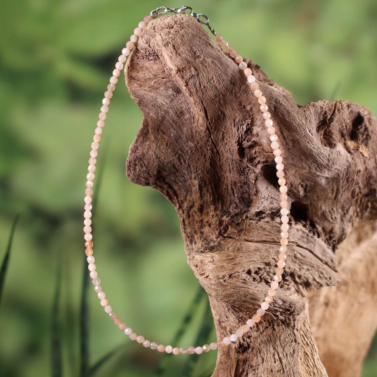 Peach-colored moonstone necklace with elegant shimmer, 41cm length, displayed on a wooden backdrop, highlighting femininity and intuition.