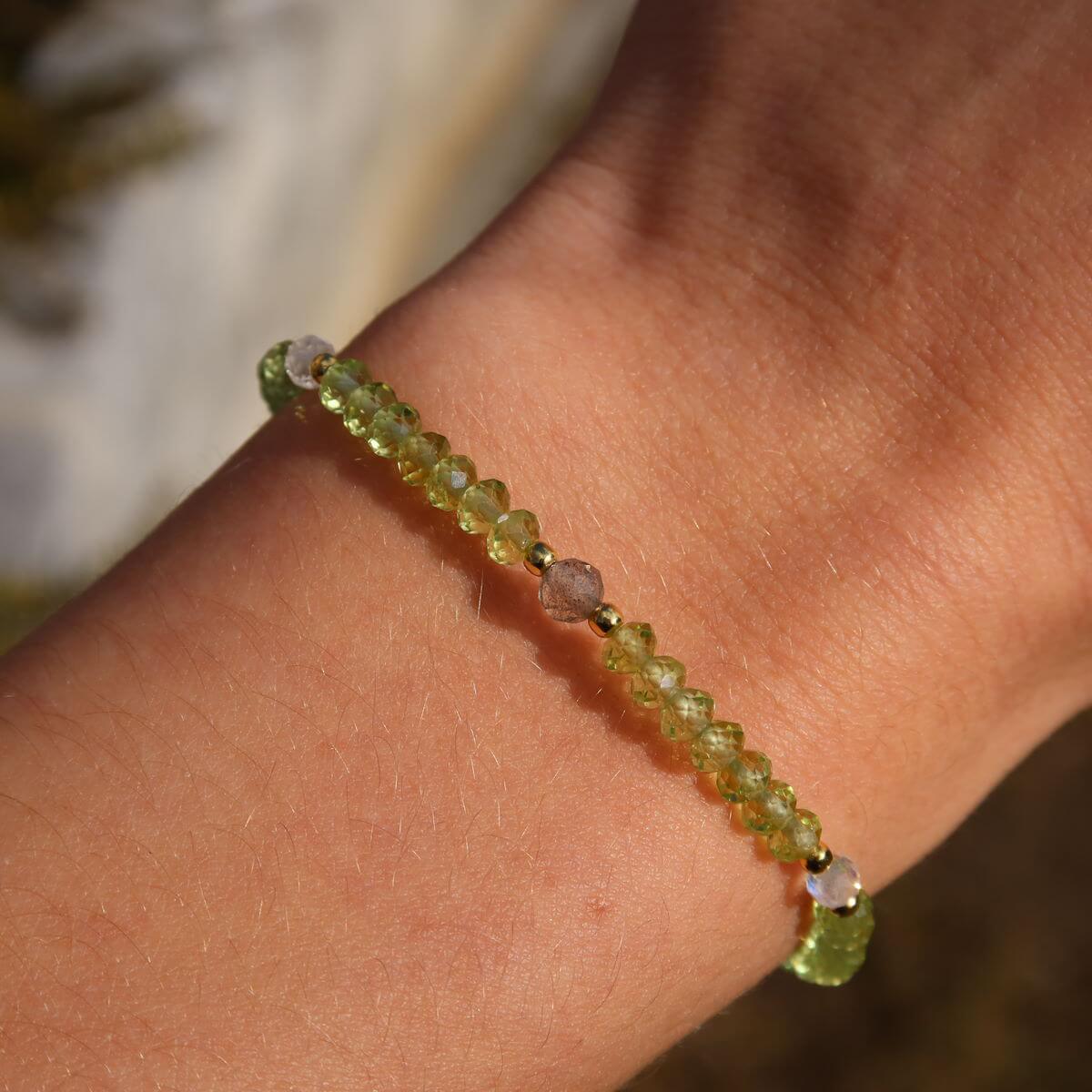 Faceted peridot and labradorite handmade gemstone bracelet on wrist, 17cm length, showcasing sparkling green and gray stones.