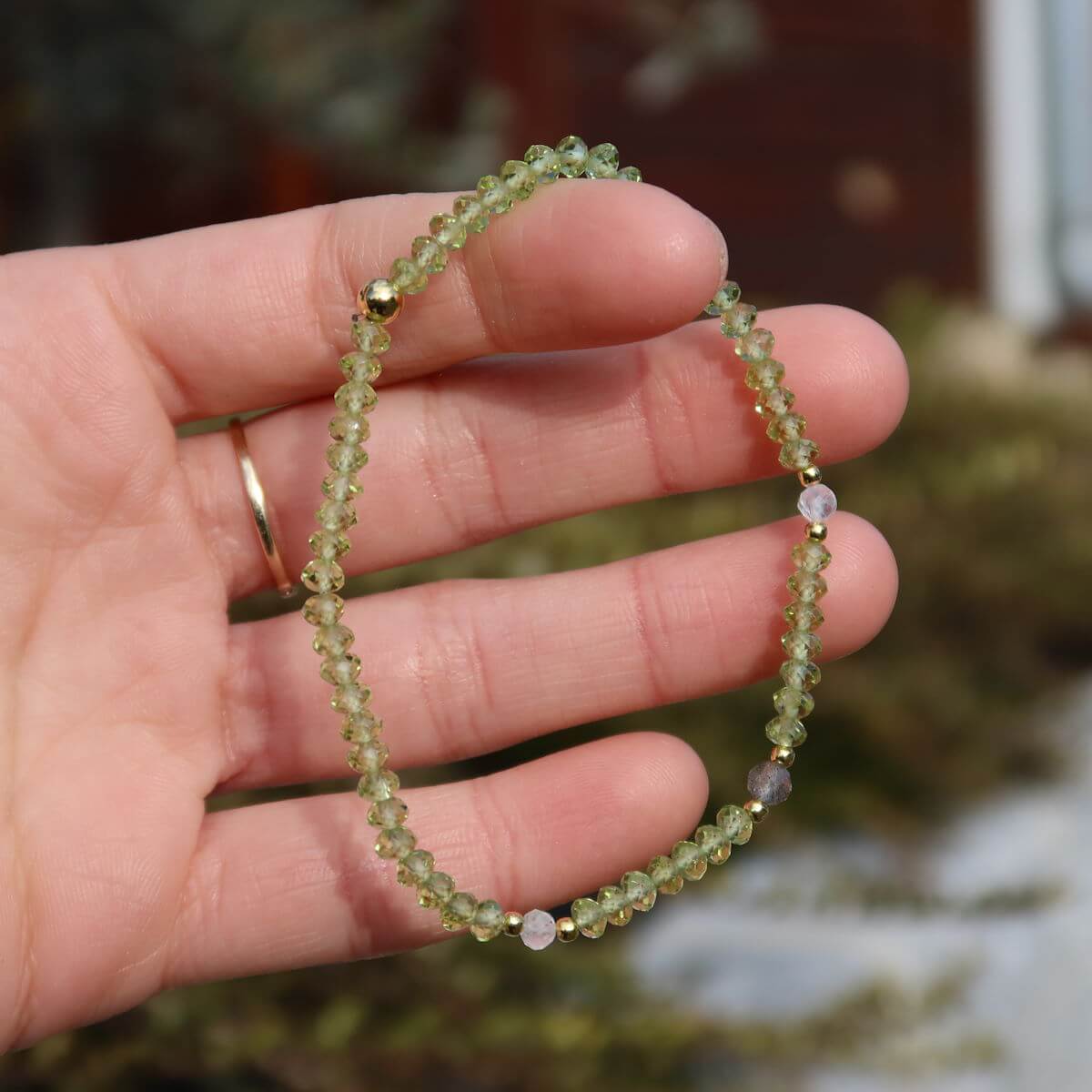 Faceted peridot and labradorite handmade gemstone bracelet on wrist, 17cm length, showcasing sparkling green and gray stones.