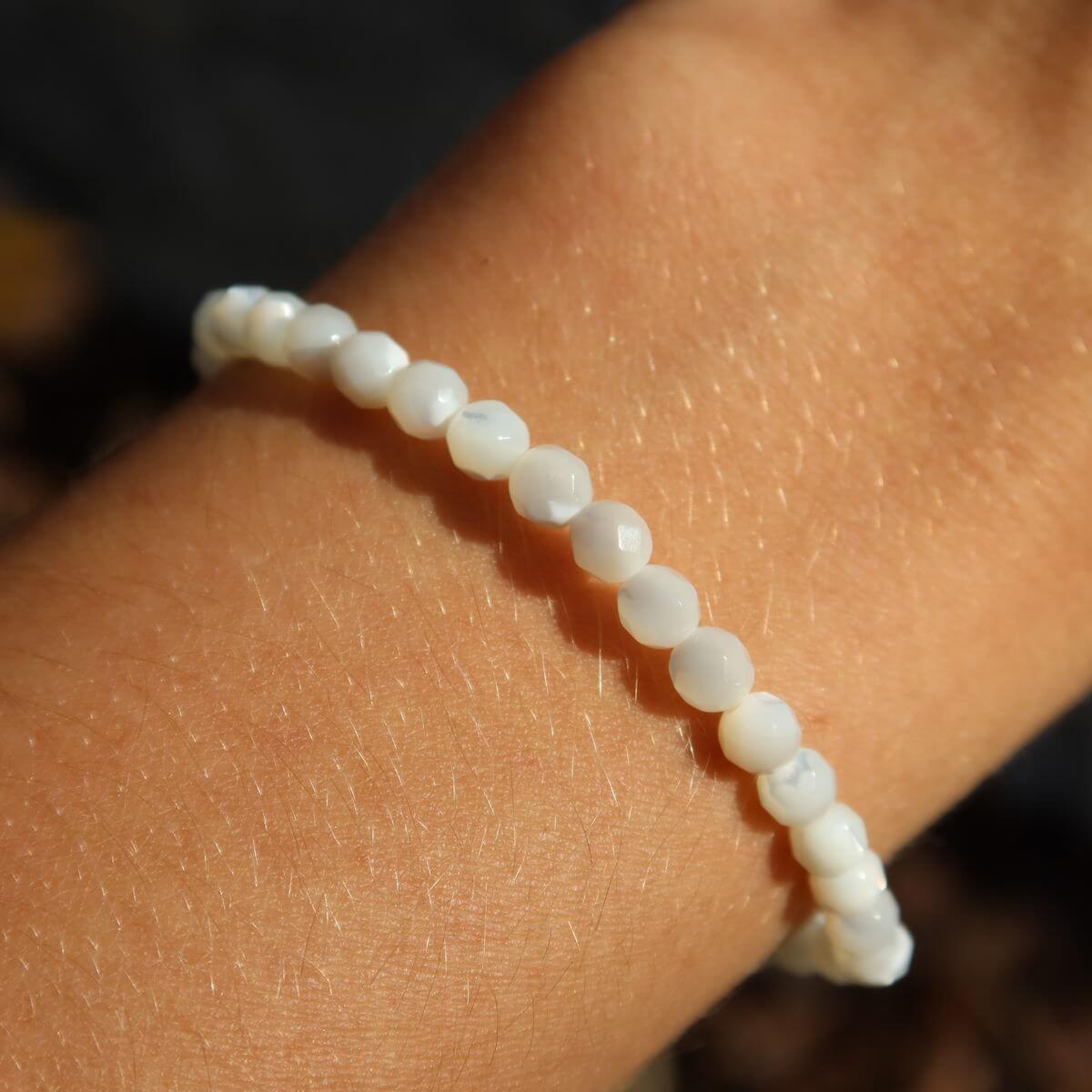 Perlmutt facettiertes Edelsteinarmband 4-6-8mm auf Handgelenk, schimmert elegant im Sonnenlicht, steht für Reinheit und Schutz.