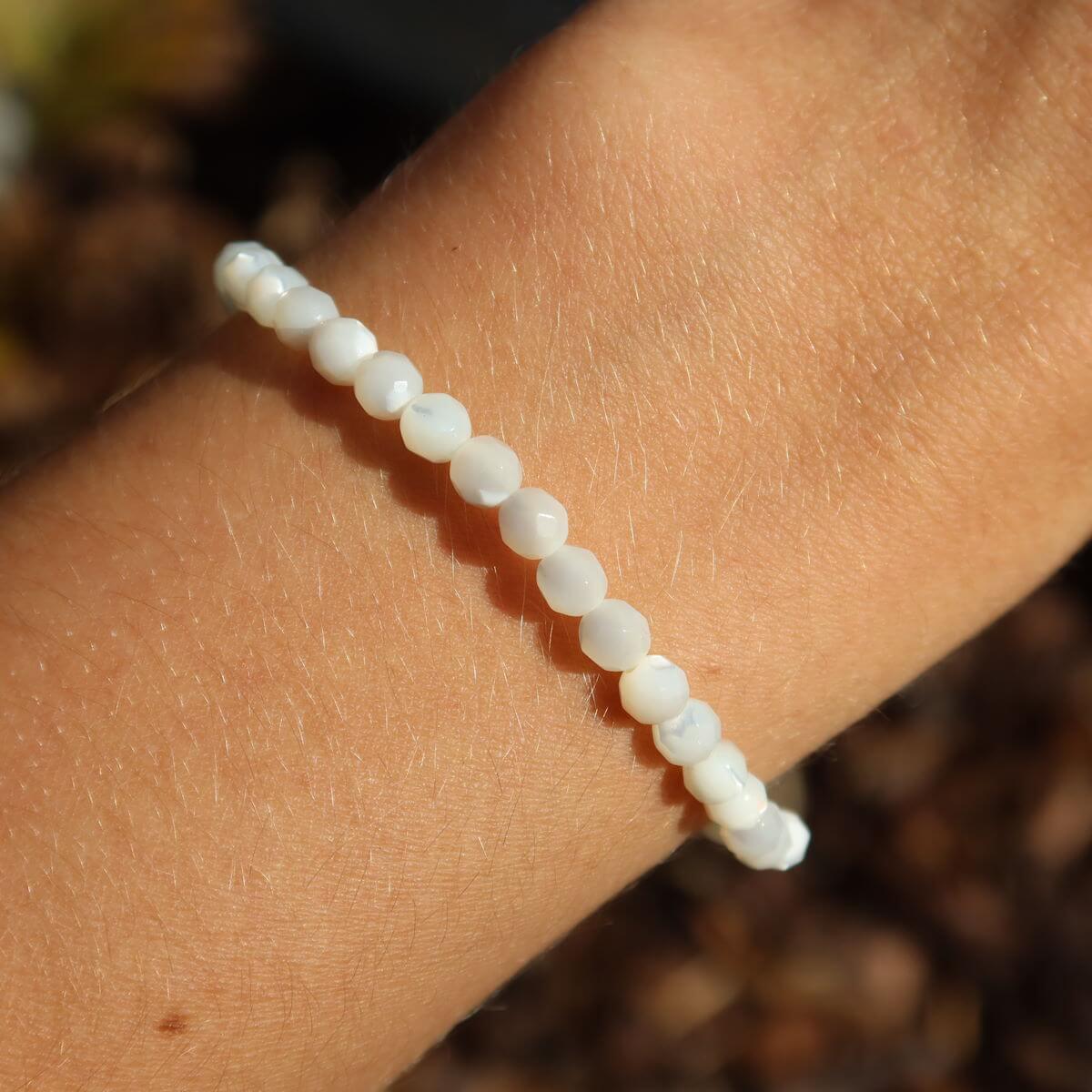 Perlmutt facettiertes Edelsteinarmband 4-6-8mm auf Handgelenk, schimmert elegant im Sonnenlicht, steht für Reinheit und Schutz.