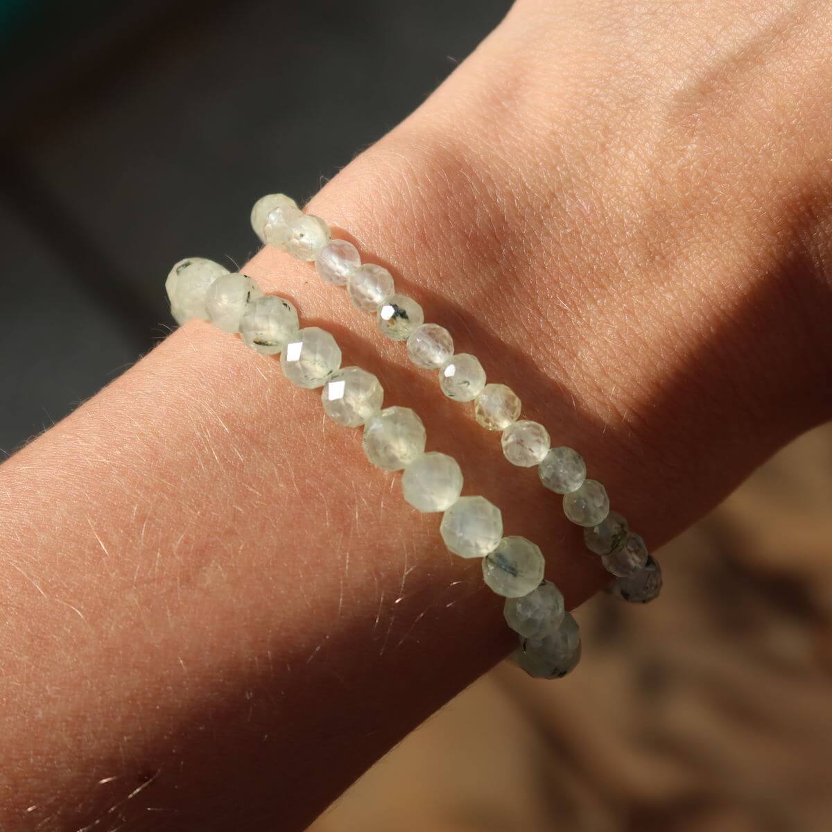 Faceted Prehnite gemstone bracelet on wrist, showcasing green hues and spiritual elegance in natural light.