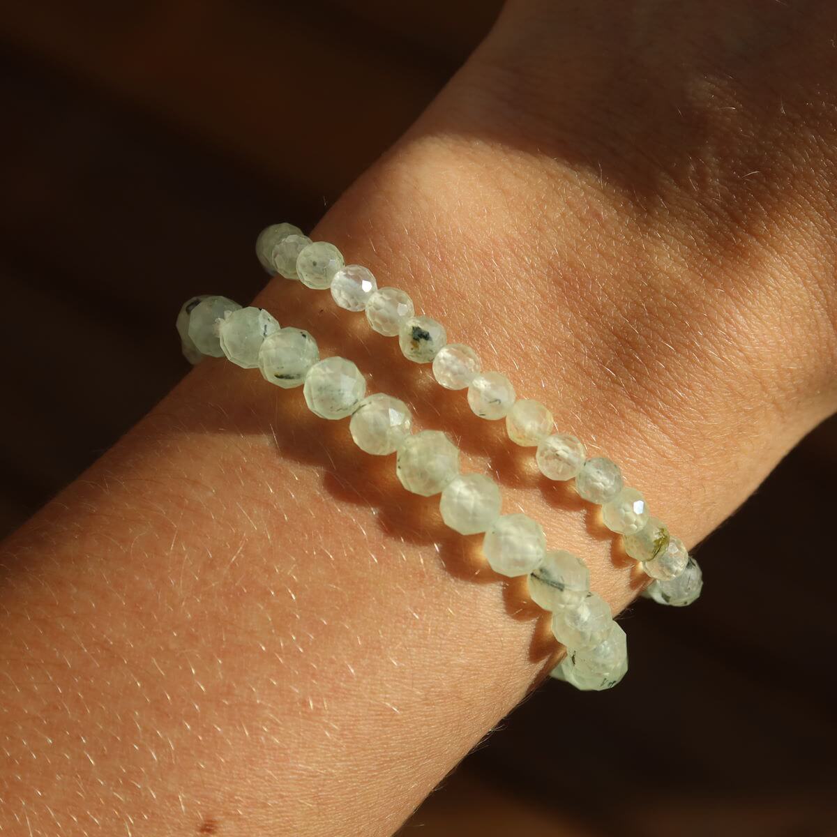 Faceted Prehnite gemstone bracelet on wrist, showcasing green hues and spiritual elegance in natural light.