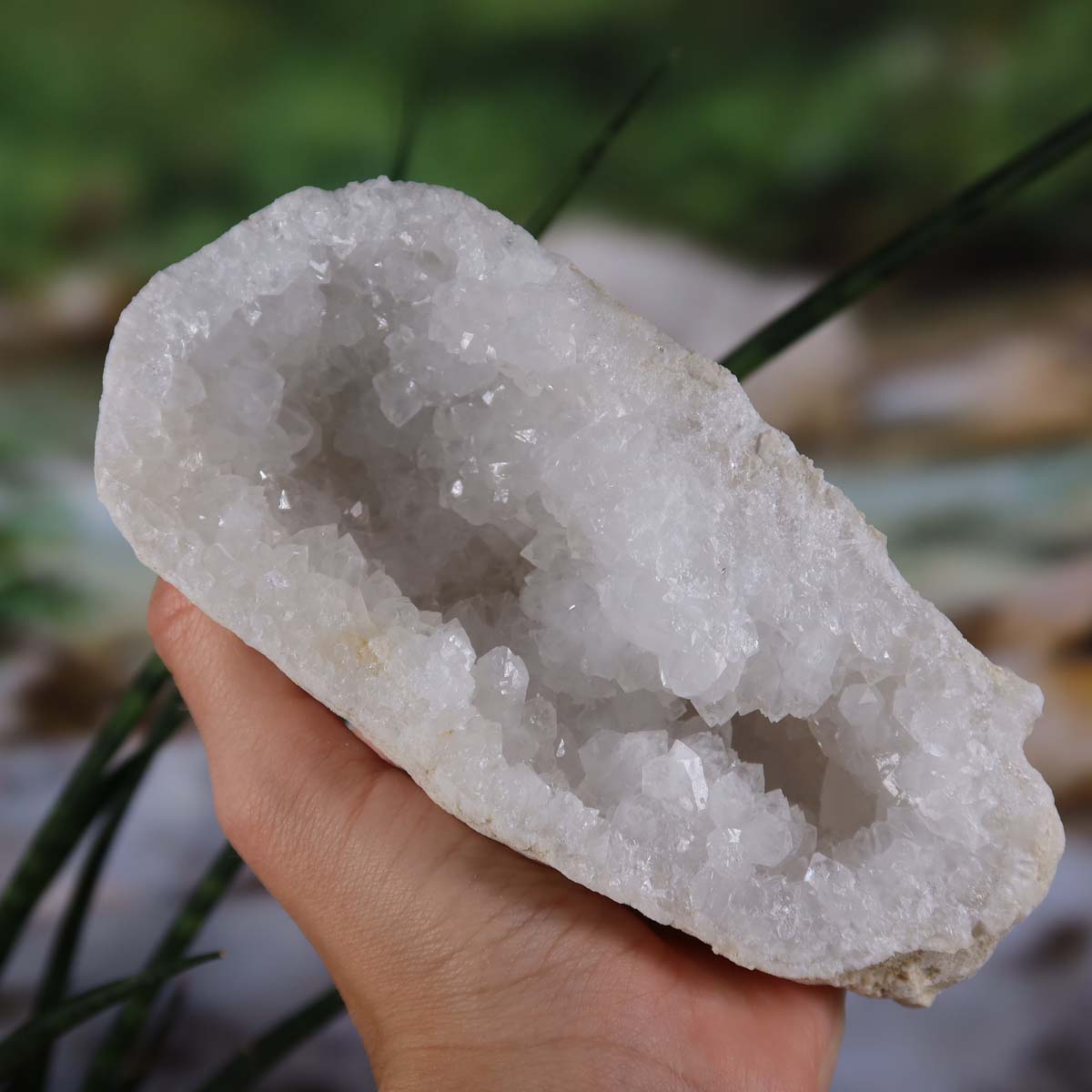 Quarz Geode geöffnet – Glücksgeode – Stabilität und Klarheit – 14x11x6 cm- Unikat Nr. 22, gehalten in einer Hand, zeigt Quarzkristalle