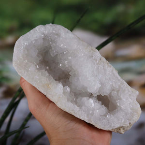 Quarz Geode geöffnet – Glücksgeode – Stabilität und Klarheit – 14x11x6 cm- Unikat Nr. 22, gehalten in einer Hand, zeigt Quarzkristalle
