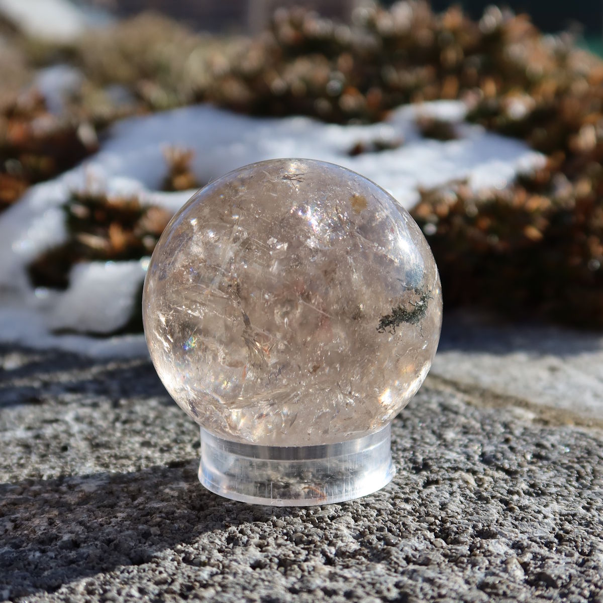 Rauchquarz Kugel – Natürliche Kristallkugel 48mm Durchmesser Nr. 47 auf steinigem Hintergrund