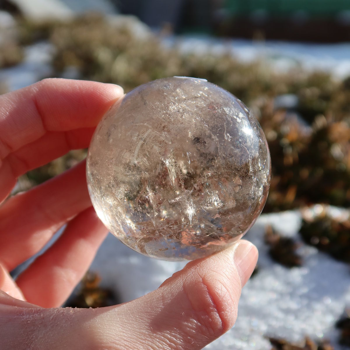 Rauchquarz Kugel – Natürliche Kristallkugel 48mm Durchmesser Nr. 47 auf steinigem Hintergrund