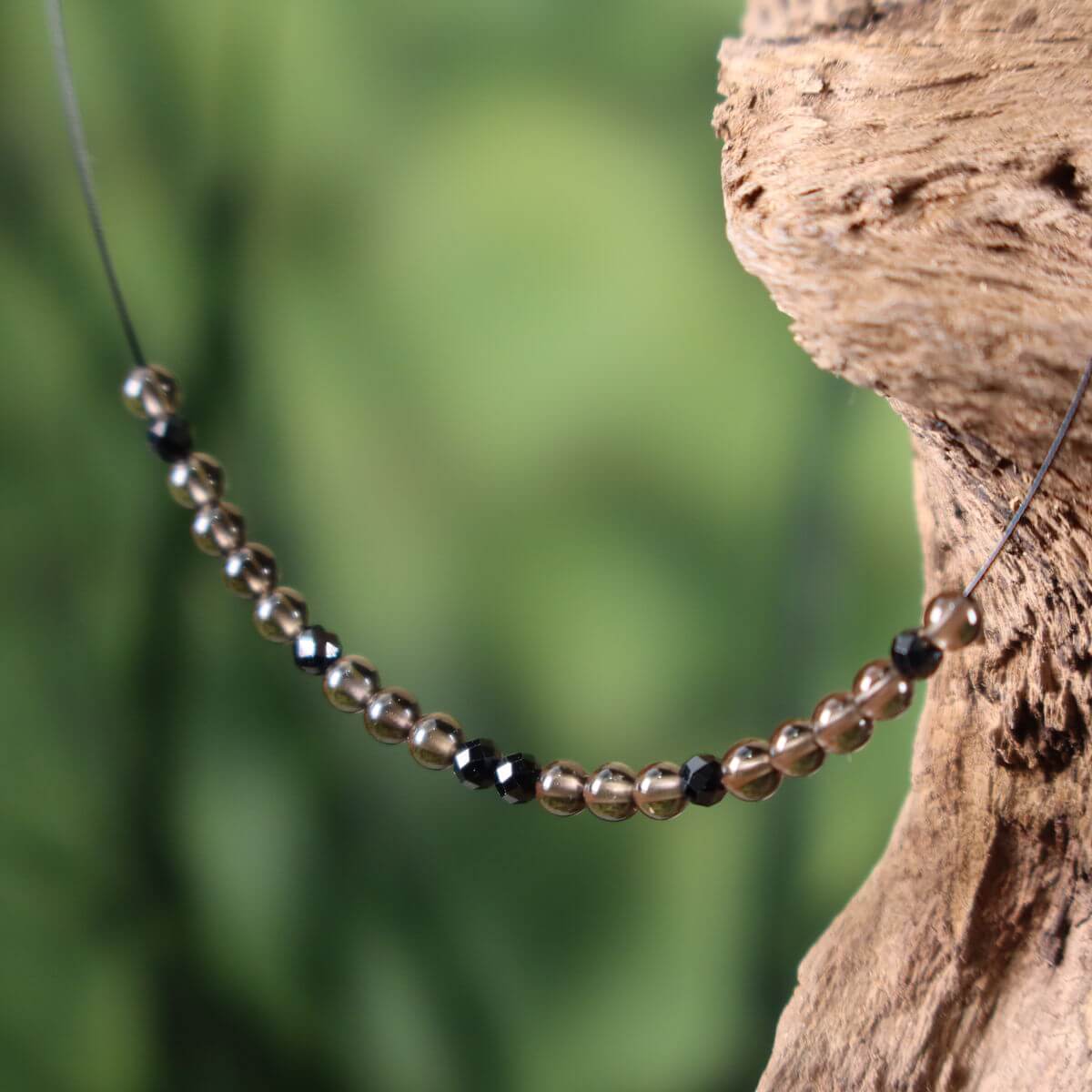 Handcrafted gemstone necklace with smoky quartz and spinel on wooden display, 40cm, for relaxation and focus.
