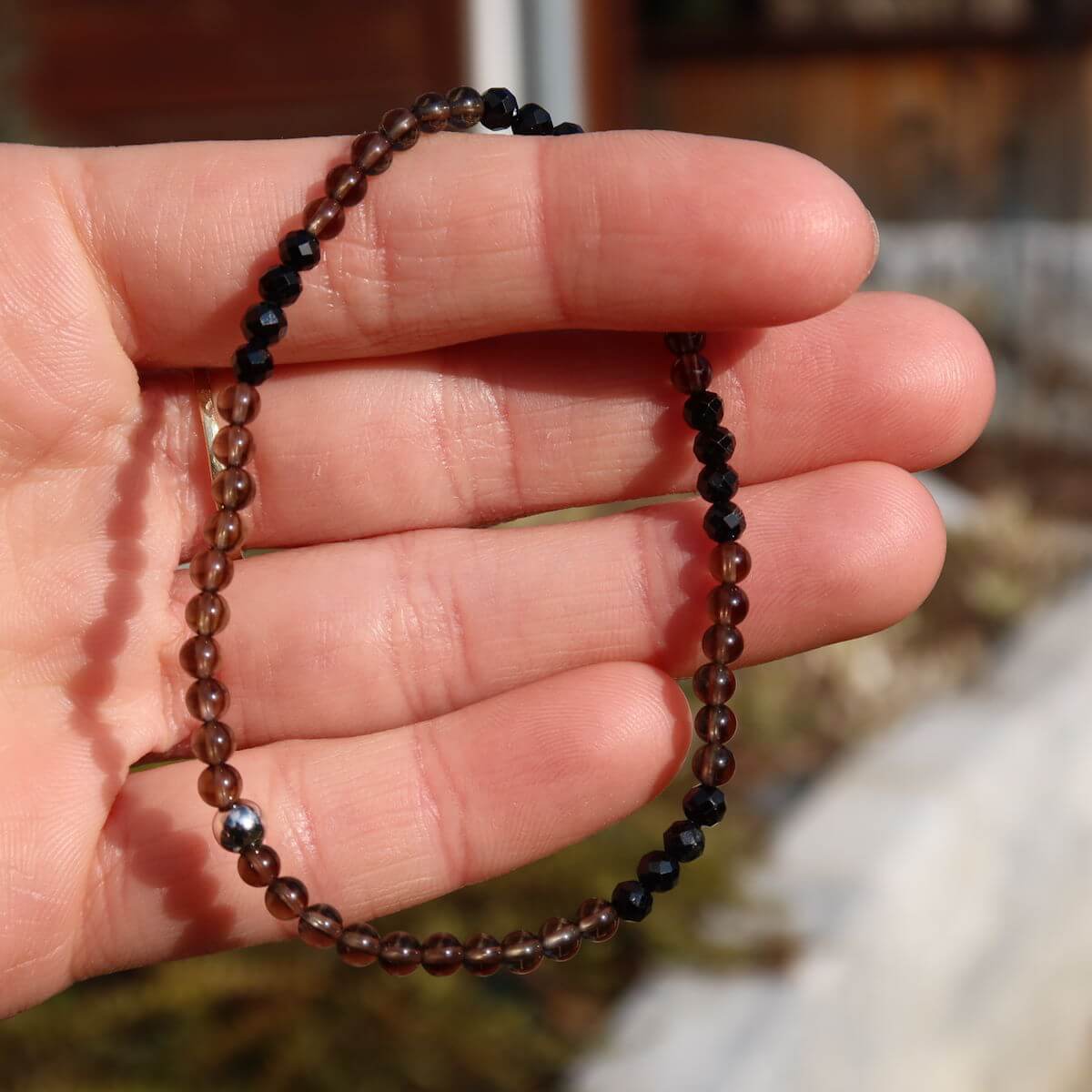 Handmade smoky quartz and black tourmaline faceted gemstone bracelet, 17cm in length, worn on a wrist.