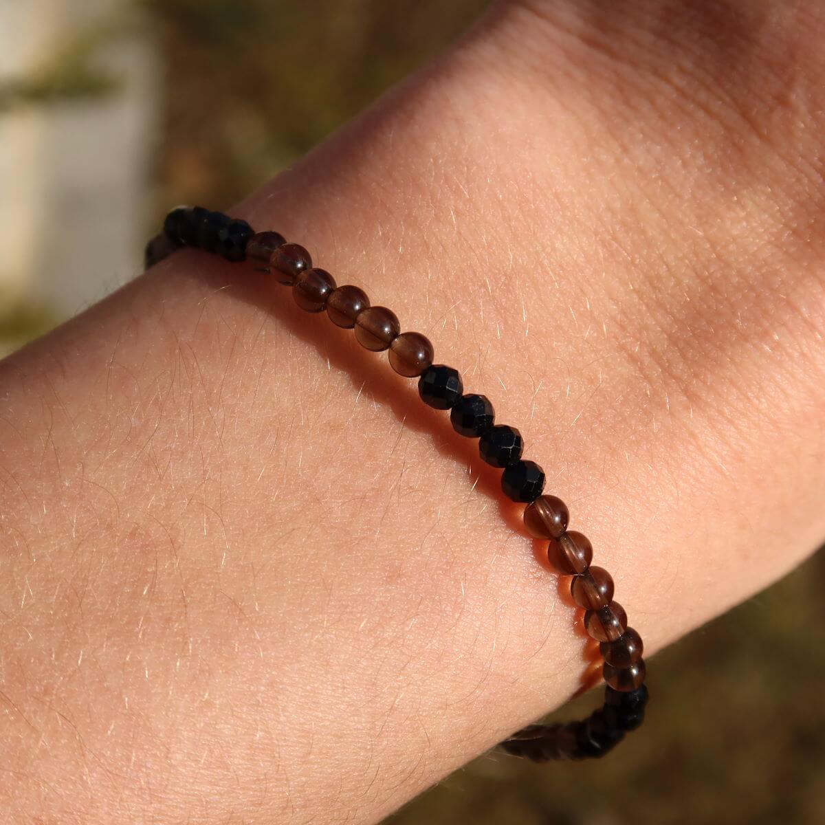Handmade smoky quartz and black tourmaline faceted gemstone bracelet, 17cm in length, worn on a wrist.
