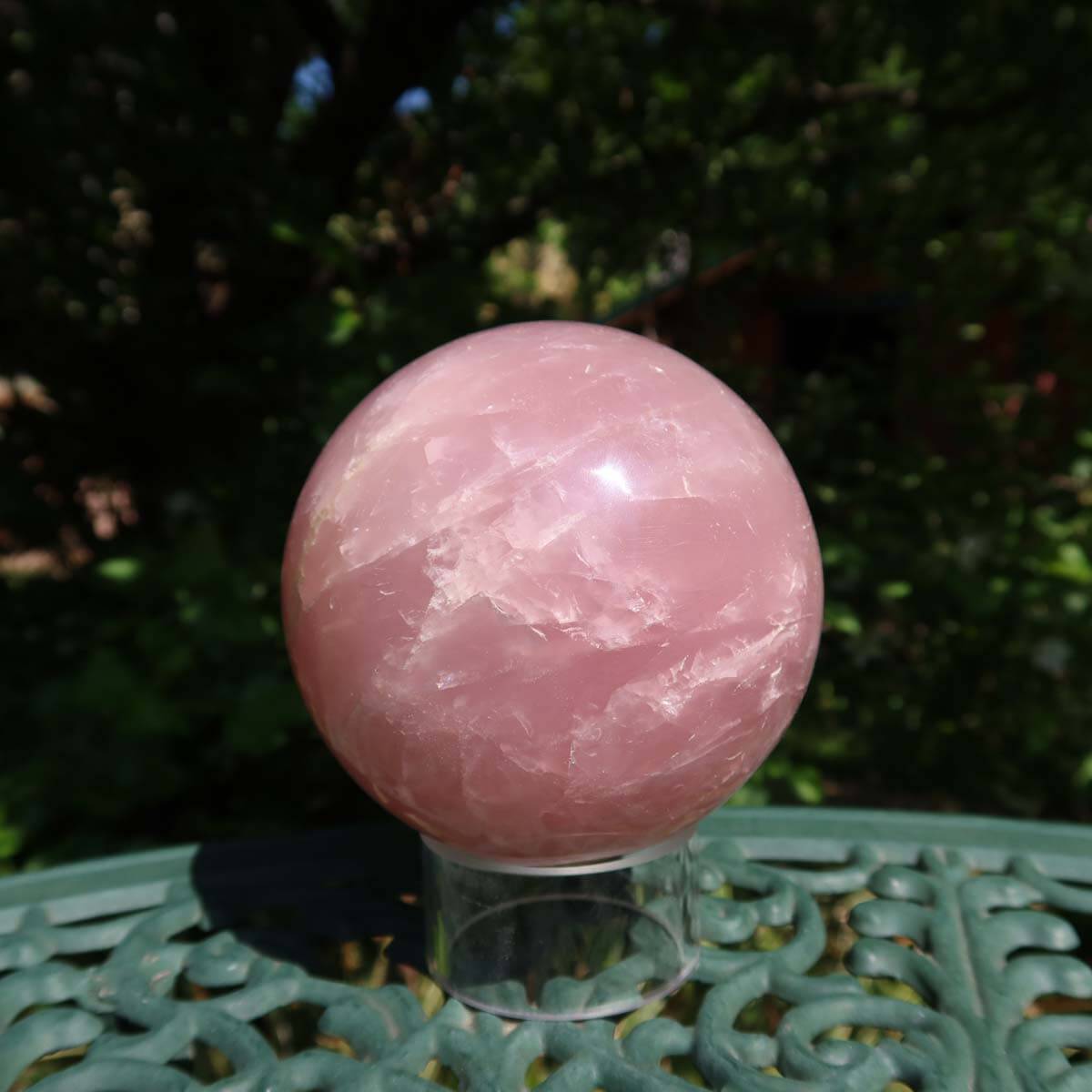 Rosenquarz Kugel, 90mm Durchmesser, auf grünem Untergrund im Freien, zeigt zarten Rosaton und klare Strukturen, Stein der Liebe