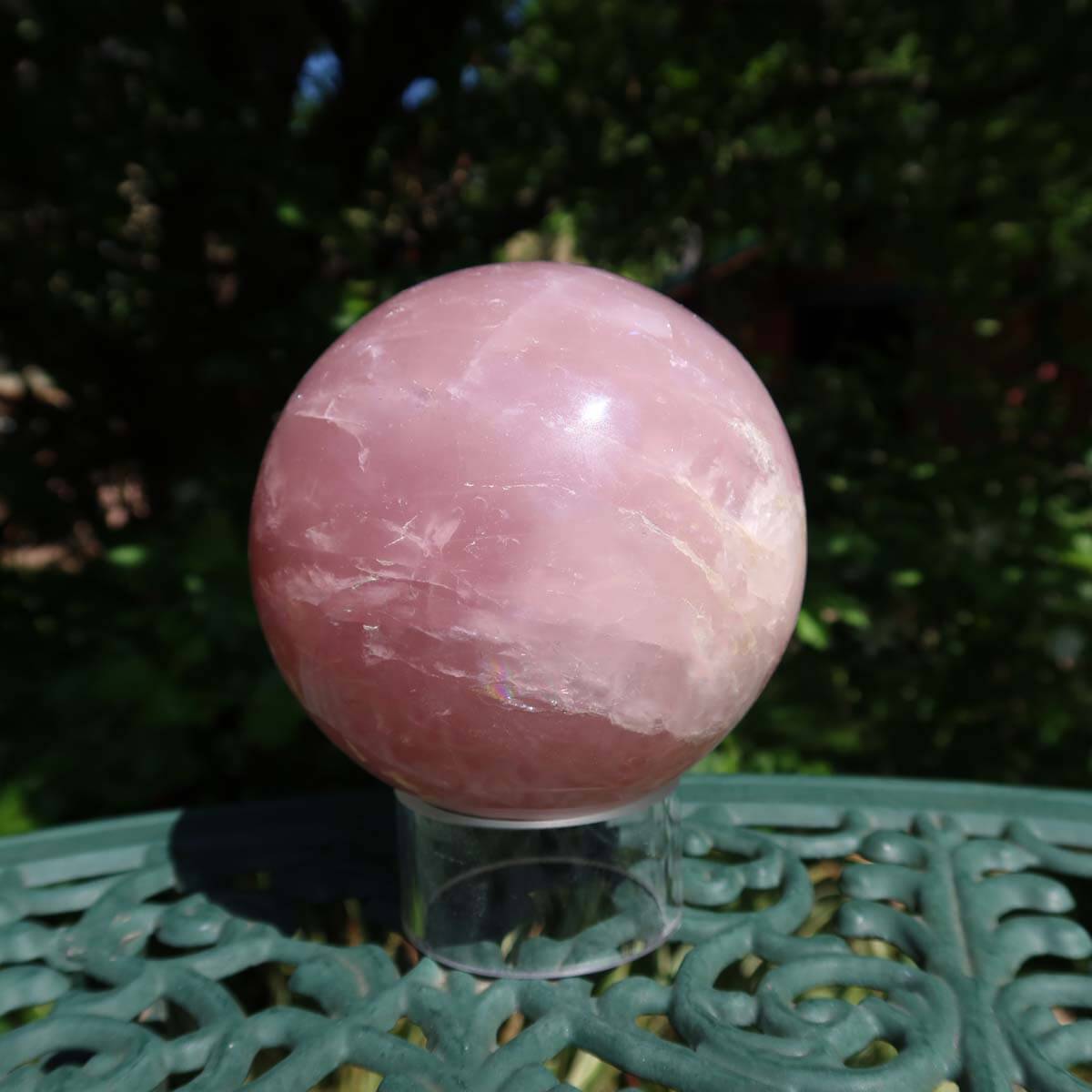 Rosenquarz Kugel, 90mm Durchmesser, auf grünem Untergrund im Freien, zeigt zarten Rosaton und klare Strukturen, Stein der Liebe