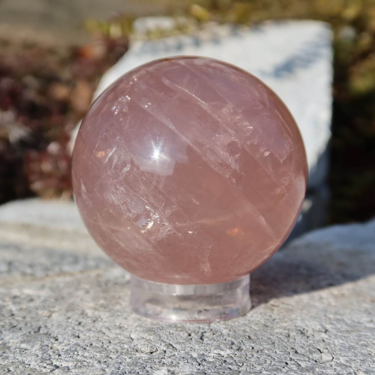 Geschliffene Rosenquarz Kugel UNIKAT Nr. 13 auf Steinoberfläche, zart rosa Farbton, hochwertiger Schmuckstein. Steinwelten online kaufen.