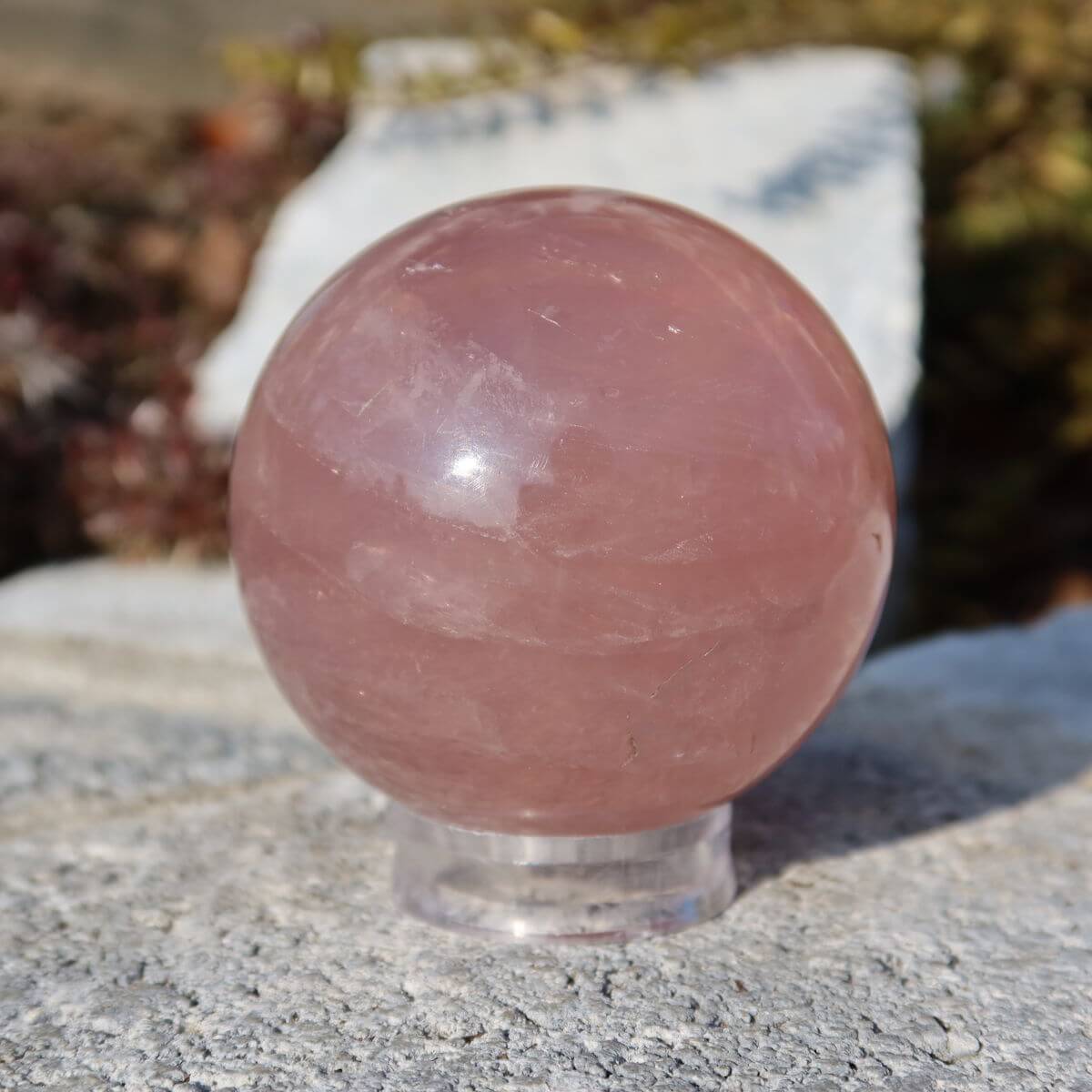 Geschliffene Rosenquarz Kugel UNIKAT Nr. 13 auf Steinoberfläche, zart rosa Farbton, hochwertiger Schmuckstein. Steinwelten online kaufen.