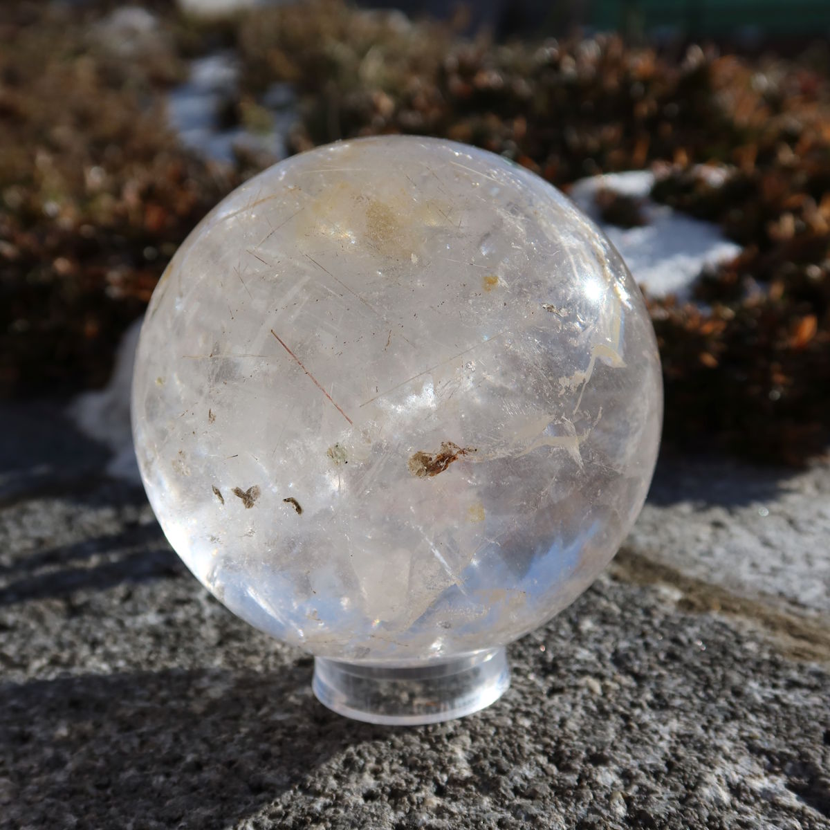 Rutilquarz Kugel – Natürliche Kristallkugel - 80mm Durchmesser Nr. 26 mit goldenen Rutilnadeln in einer Hand im Freien gehalten