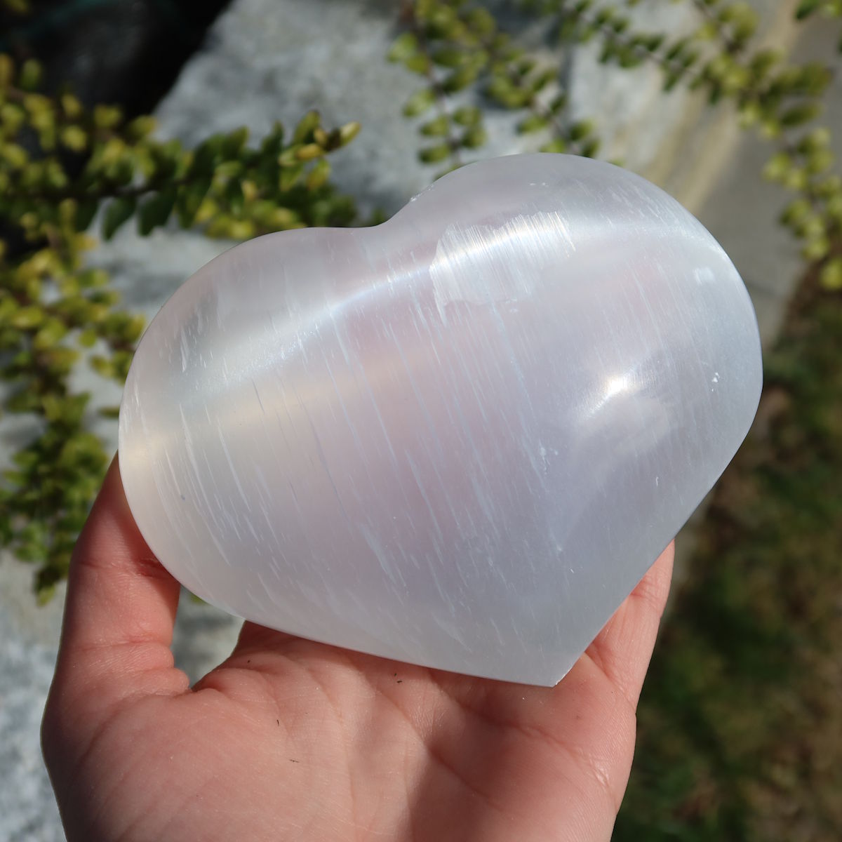 Selenit Herz - Handschmeichler - 8cm - Schutzstein für Stabilität und Nervenstärkung im Freien auf einer Hand gehalten
