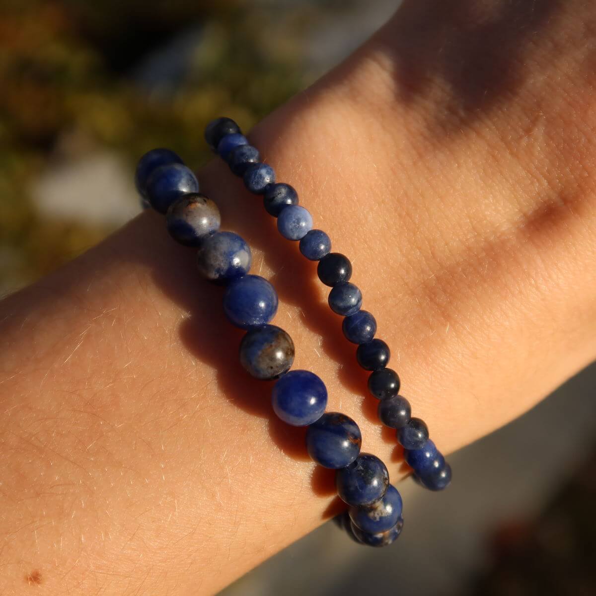Hand holding Sodalith gemstone bracelets with 4mm and 6mm beads, ideal for slim wrists, available at Steinwelten Graz and Wiener Neustadt.
