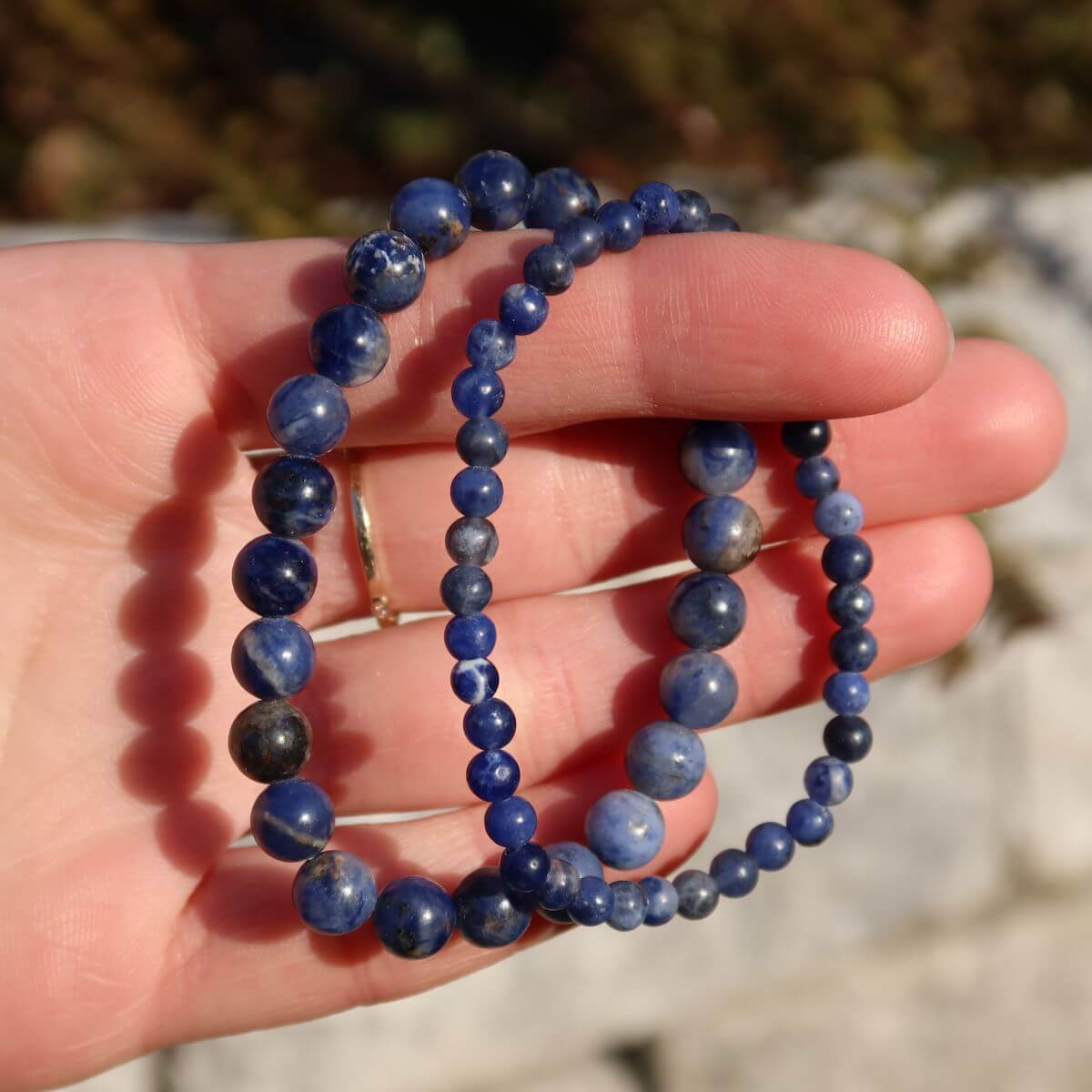 Hand holding Sodalith gemstone bracelets with 4mm and 6mm beads, ideal for slim wrists, available at Steinwelten Graz and Wiener Neustadt.