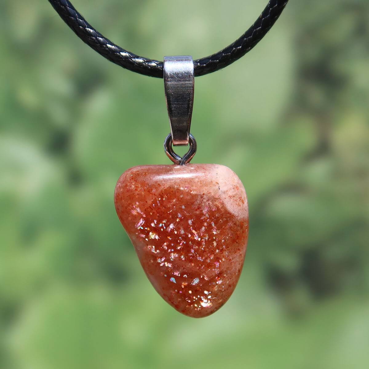 Natürlicher Sonnenstein Anhänger mit Silberschlaufe, poliert, warm orange Farbtöne, Unikat Nr. 10, auf schwarzem Ledereinband