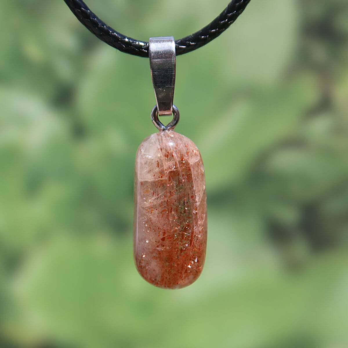 Natürlicher Sonnenstein Anhänger mit Silberschlaufe, 22mm, warmes Gold bis kräftiges Orange, Unikat Nr. 17 auf grünem Hintergrund.