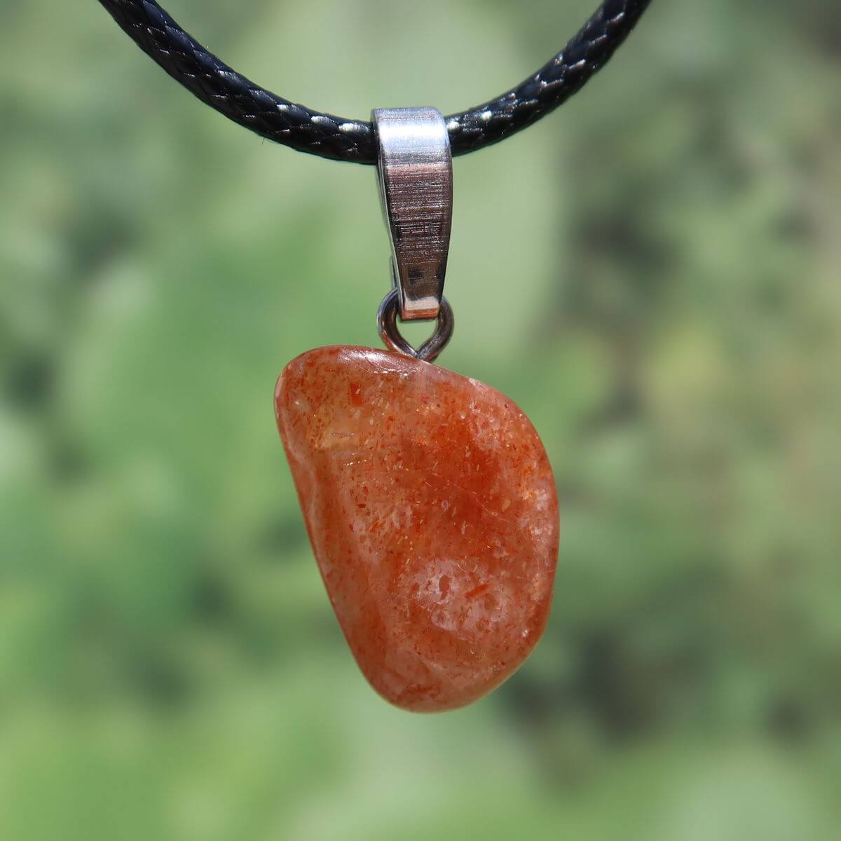 Natürlicher polierter Sonnenstein Anhänger mit Silberschlaufe und schwarzer Kordel, einzigartig und leuchtend in warmen Farbtönen.