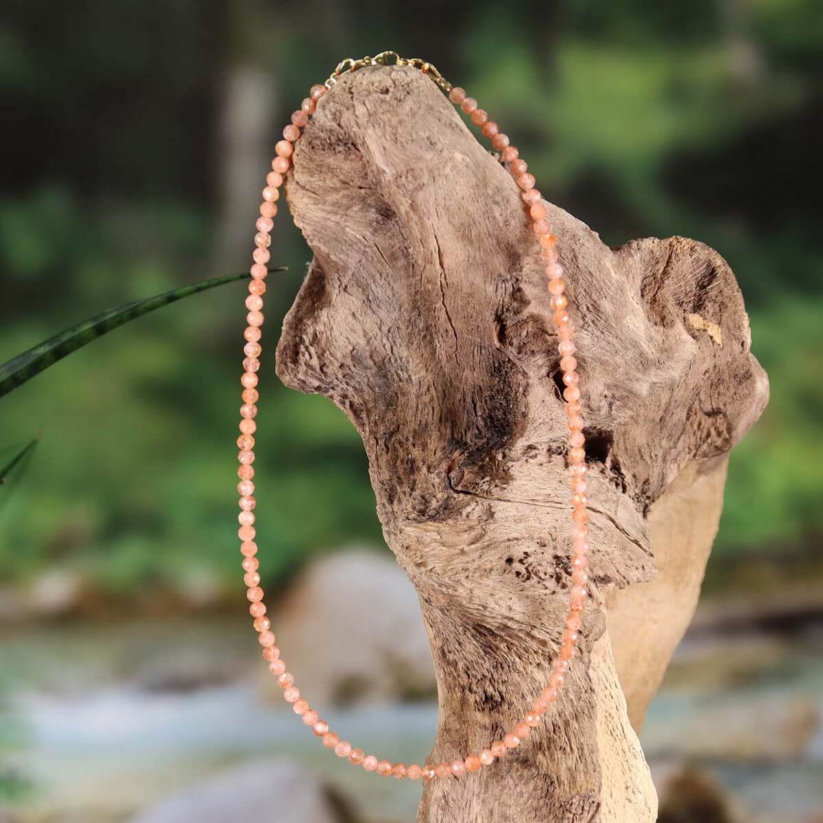 Sonnenstein facettierte Edelsteinkette 42cm mit Pfirsich-Schimmer auf Holz ausgestellt - Steinwelten kaufen online.