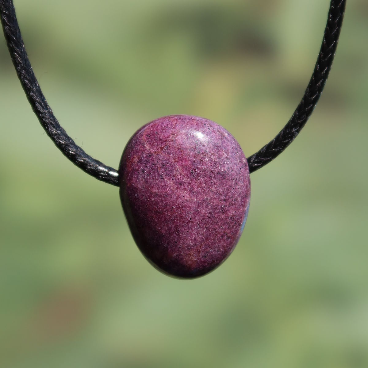 Natürlicher Stichtit gebohrt 21mm - innere Ruhe und Gelassenheit - UNIKAT Nr. 10 in Nahaufnahme vor grünem Hintergrund