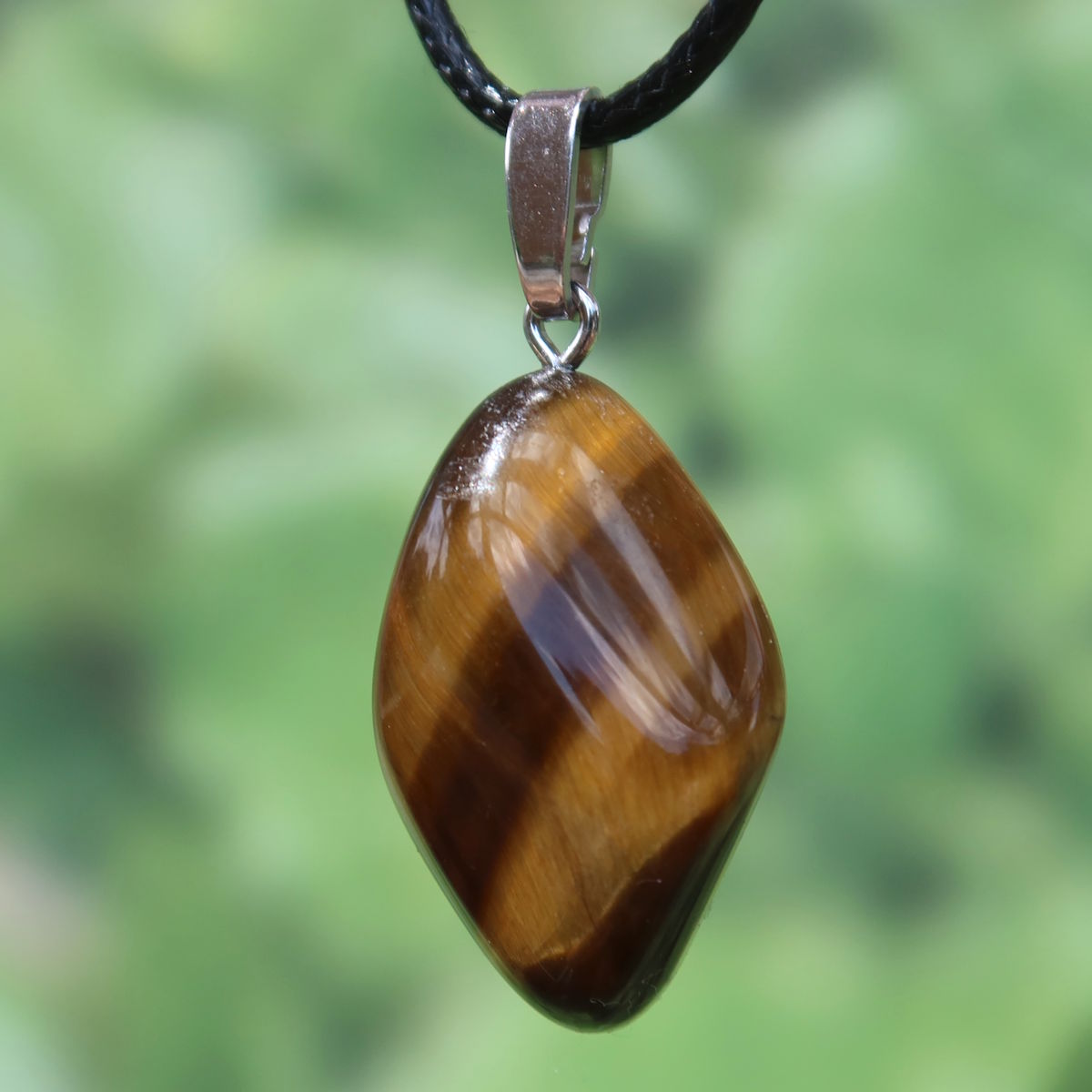 Tigerauge Anhänger 31mm - Selbstbewusstsein und Konzentration - UNIKAT Nr. 7, glänzender Schmuck mit markanten Streifen auf grünem Hintergrund.